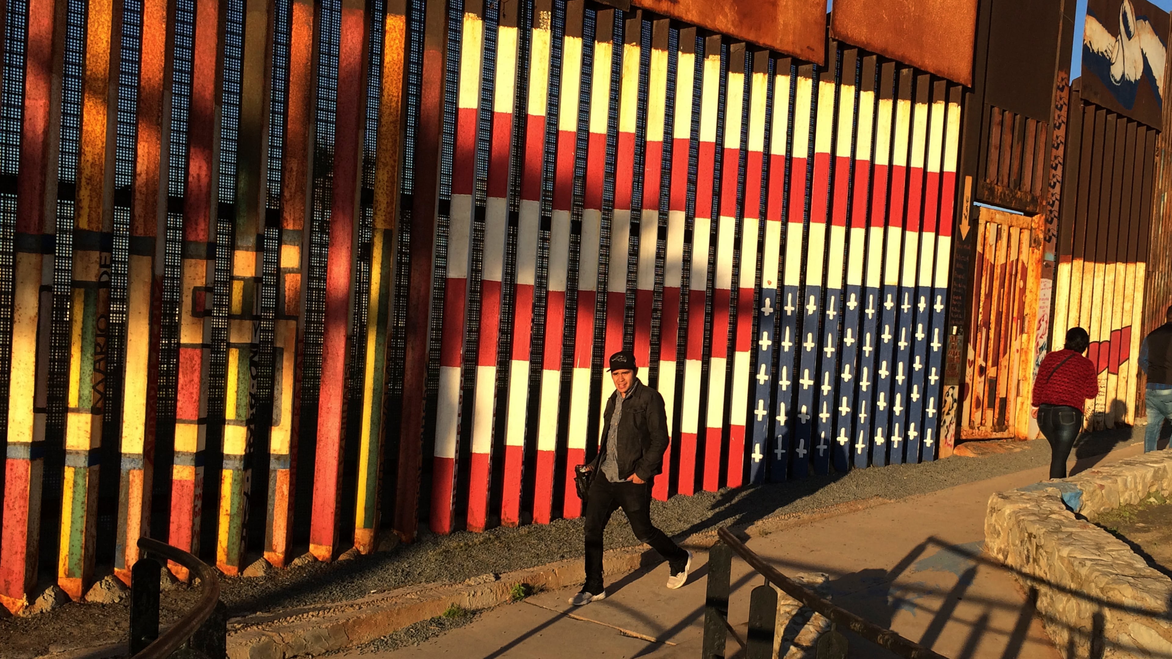 People pass graffiti along the border structure in Tijuana, Mexico, Wednesday, Jan. 25, 2017. President Donald Trump moved aggressively to tighten the nation's immigration controls Wednesday, signing executive actions to jumpstart construction of his promised U.S.-Mexico border wall and cut federal grants for immigrant-protecting "sanctuary cities." (AP Photo/Julie Watson)