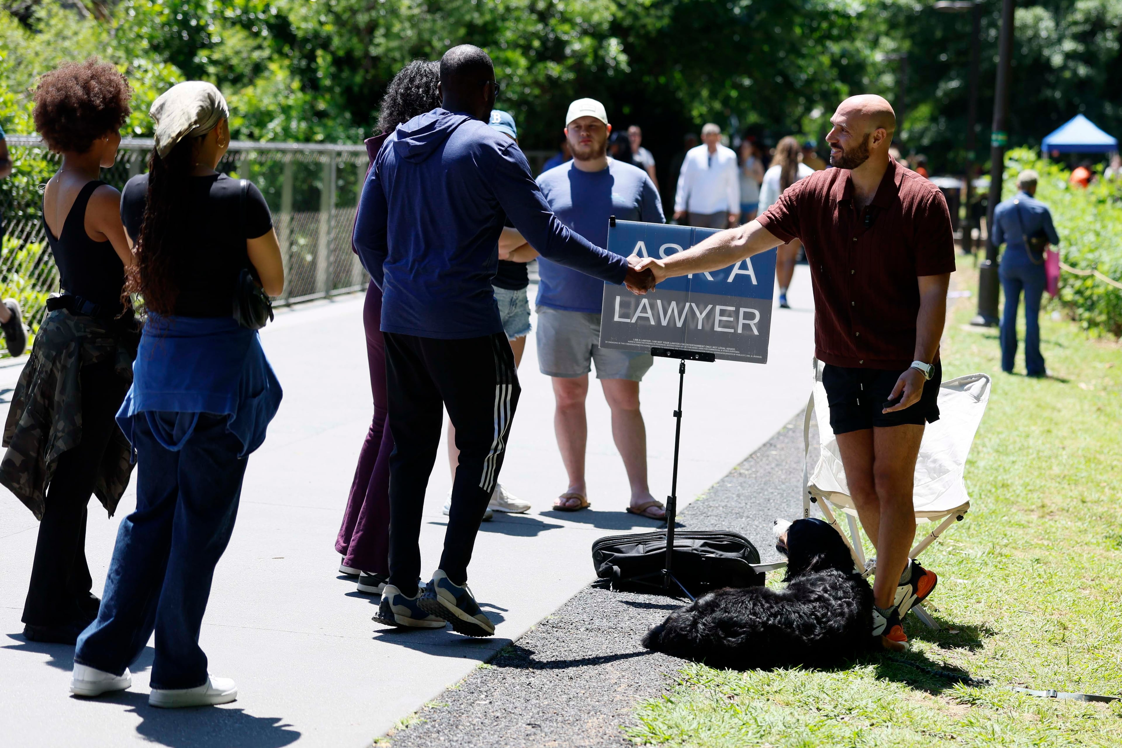 Attorney Cody Randall greets visitors as they begin to line up for him at his station on the Beltline. Randall usually spends a few weekend hours in public with his "Ask A Lawyer" sign and Reba, his 6-year-old Bernese Mountain Dog, two or three times a month, often on the Beltline close to his home in West Midtown. (Miguel Martinez/AJC)