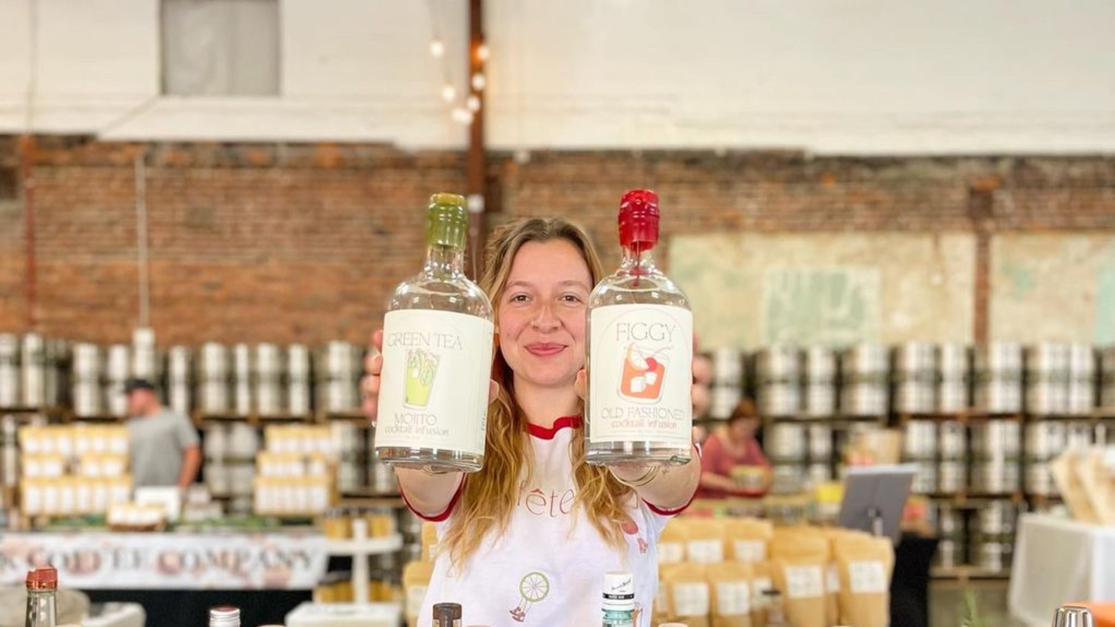 Marguerite Seckman holds up several different cocktail bottles while at the Makers Market.