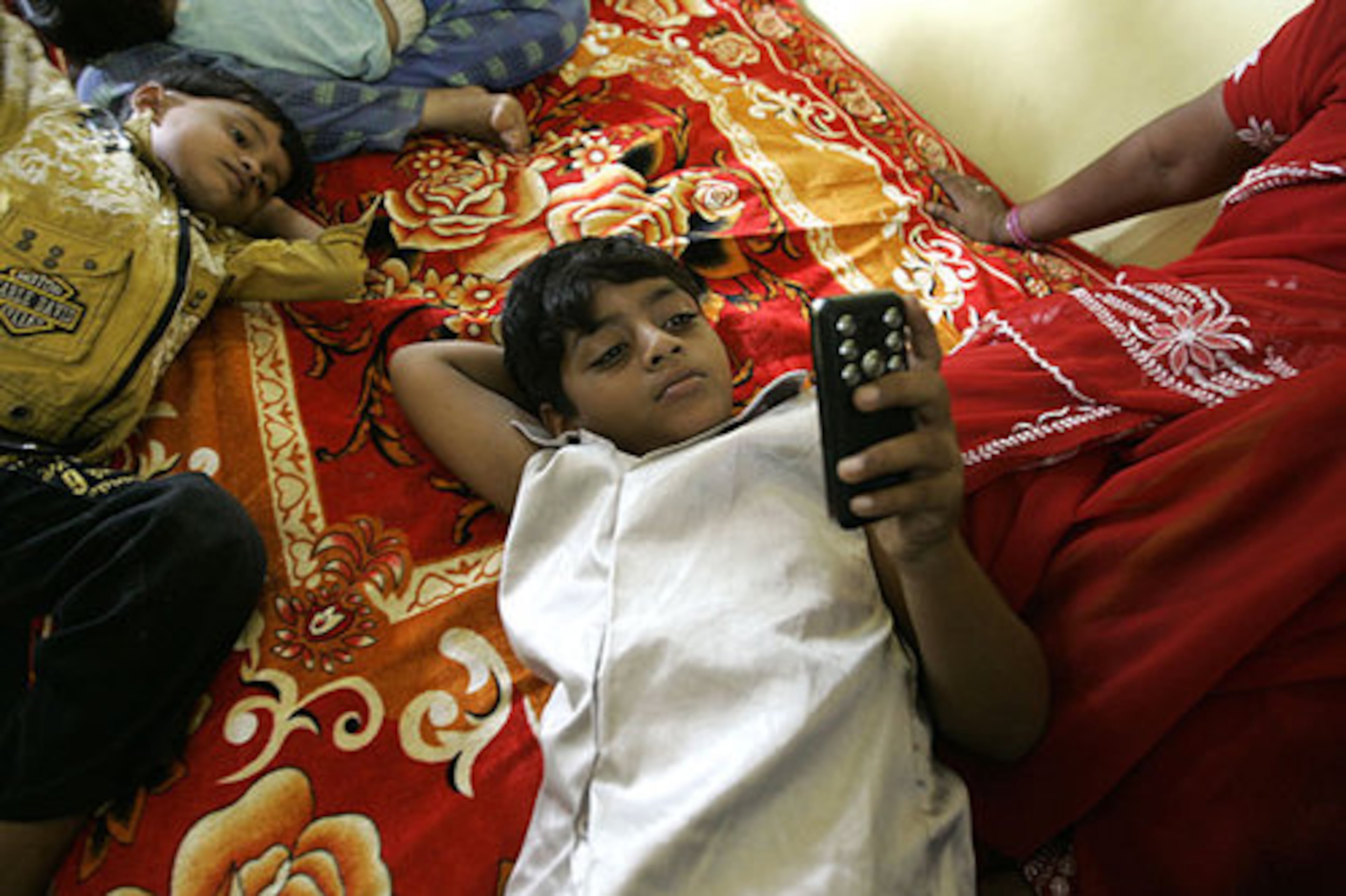 Azharuddin Mohammed Ismail, center, plays with a mobile phone at his new home. Ismail and his mother had lived in a corrugated metal shanty.