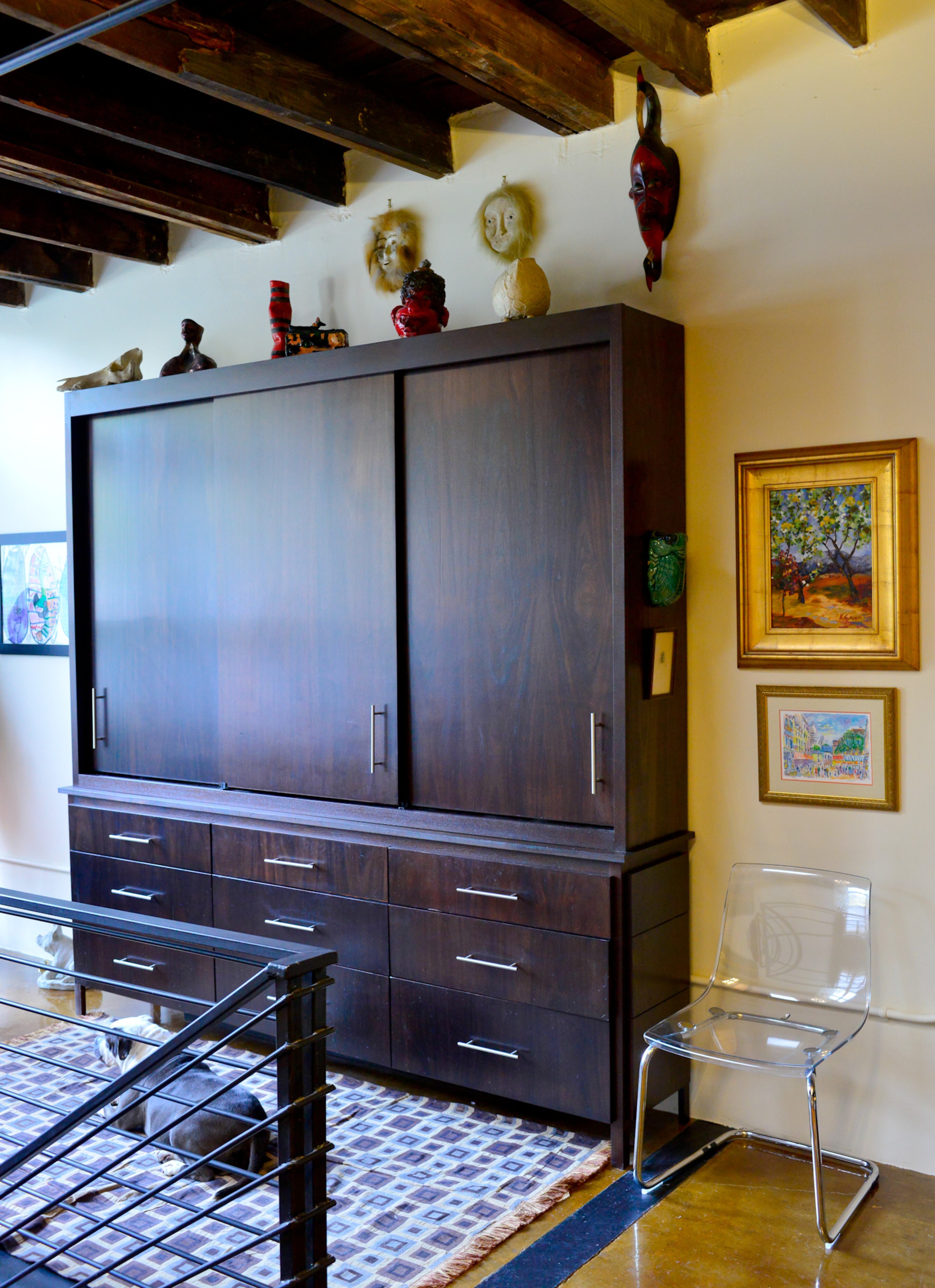 Storage was lacking, so Greg Michael of Mi-Kin Creations in Kennesaw built custom storage units for Thomas and Betsy Walsh on two floors of their Atlanta loft, which has original exposed beams. Artwork flanks a storage unit near the front door, including a framed sketch made when Betsy's daughter was in elementary school (to the left of the unit).