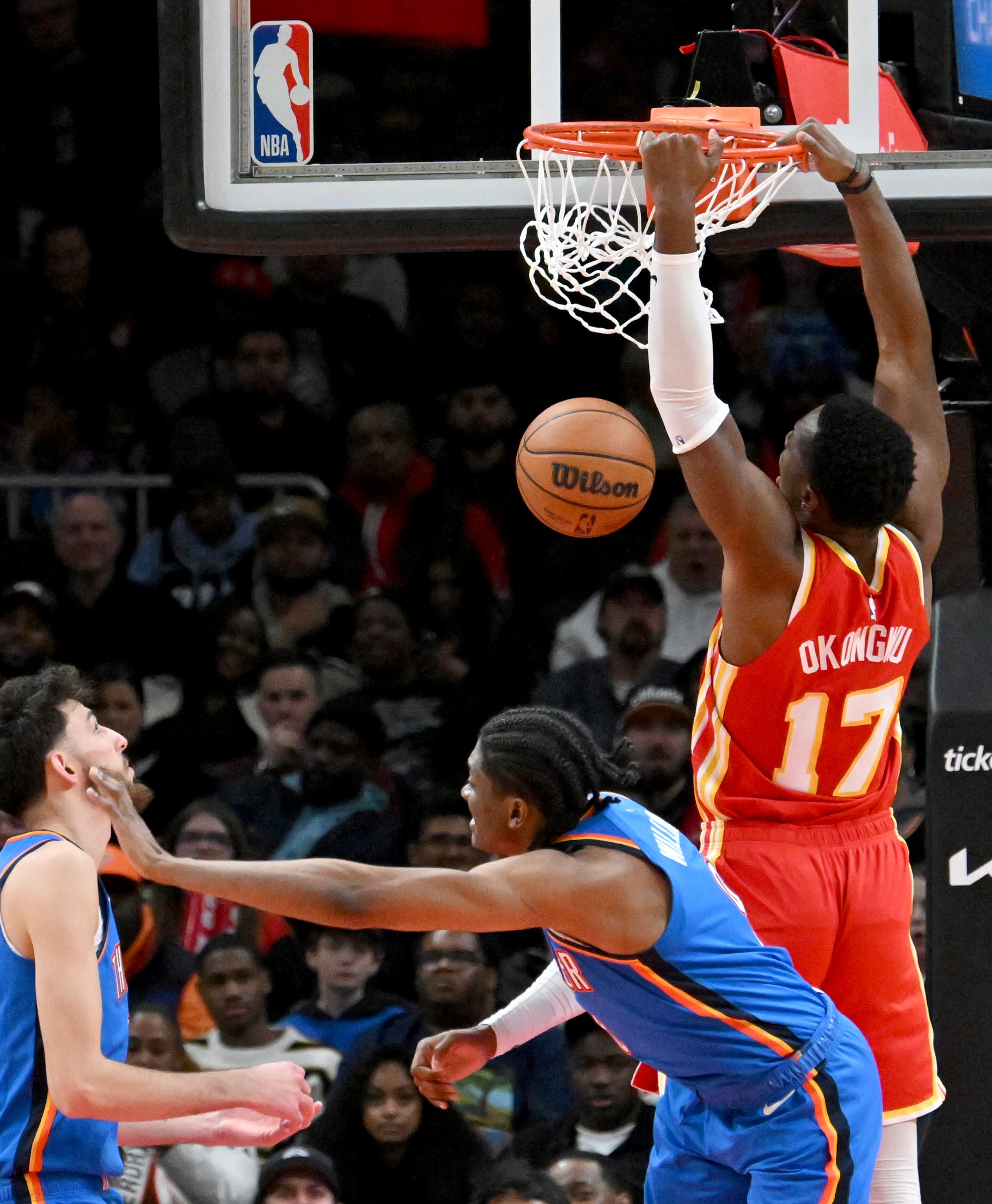 Atlanta Hawks forward Onyeka Okongwu (17) hangs on the basket after dunking the ball during the second half in an NBA basketball game at State Farm Arena, Wednesday, December 3, 2024, in Atlanta. Atlanta Hawks won 141-138 over Oklahoma City Thunder. (Hyosub Shin / Hyosub.Shin@ajc.com)