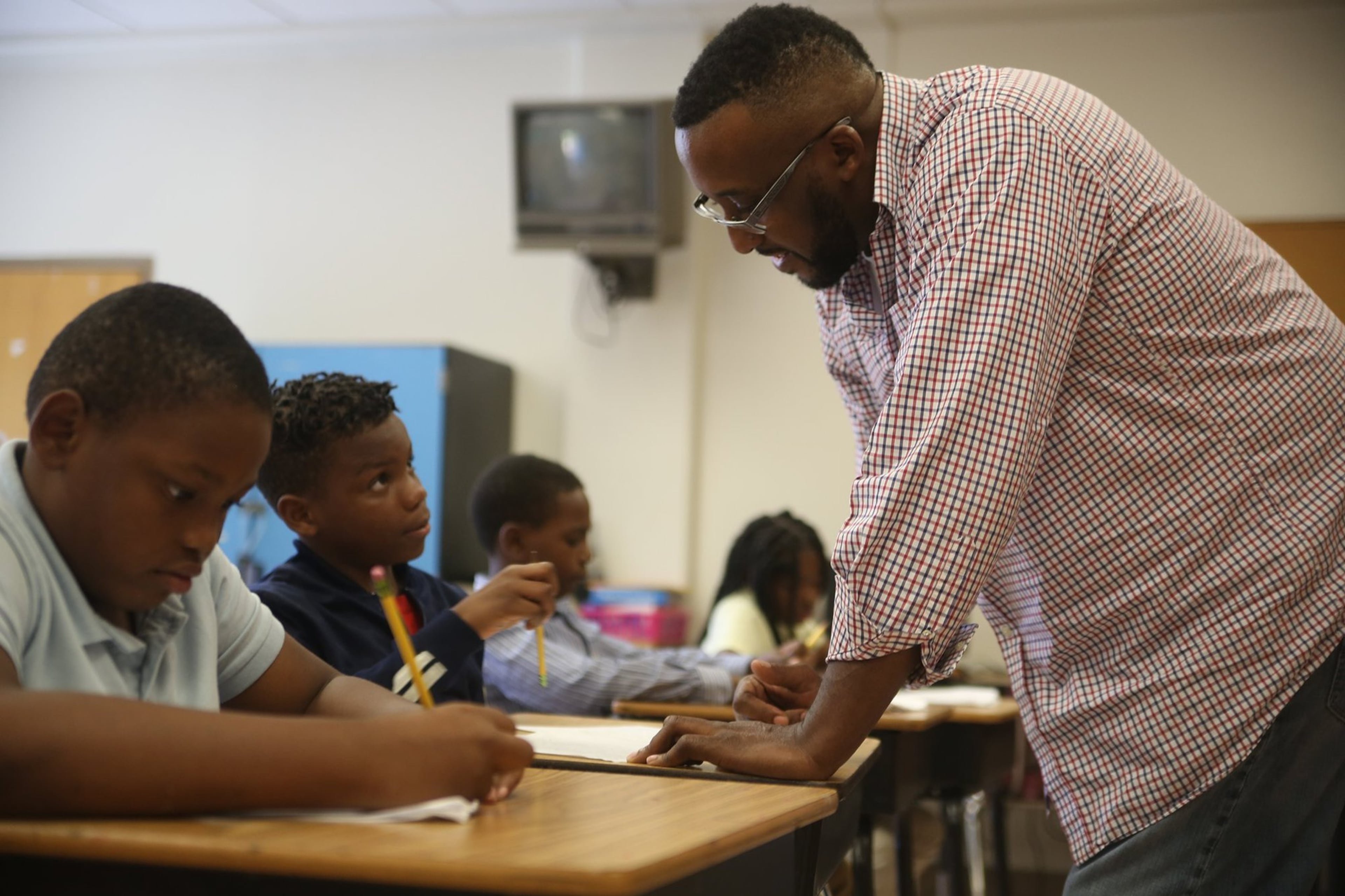 Fourth grade teacher Thaddeus Dawsey helps Jeremiah Jones (second from left) through an academic exercise at Gideons Elementary School.