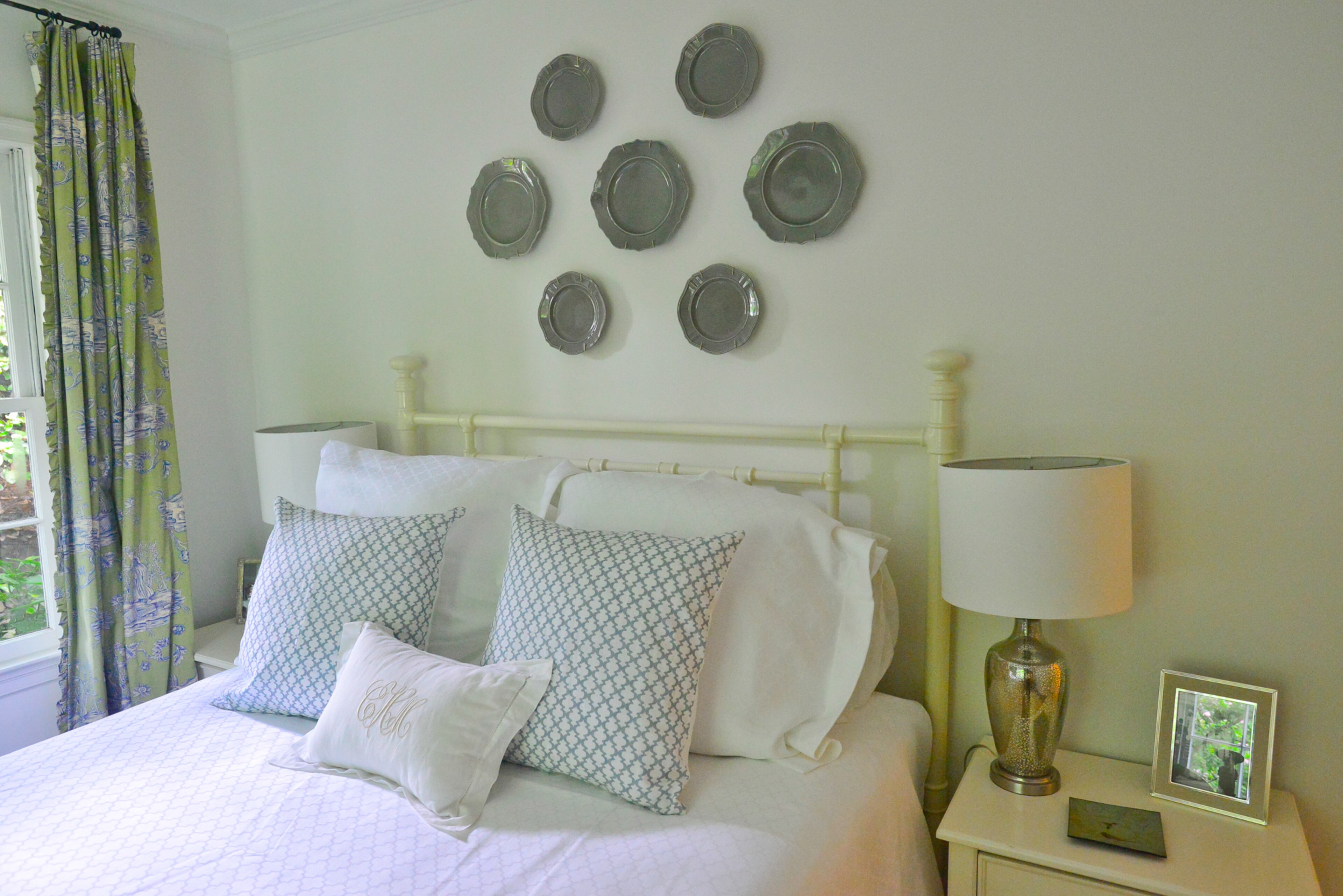 The bed and end tables from Havertys are topped with linens from Erika Reade in a guest room. The plates above the headboard also are from Erika Reade in Atlanta, with lamps from Ballard Designs.