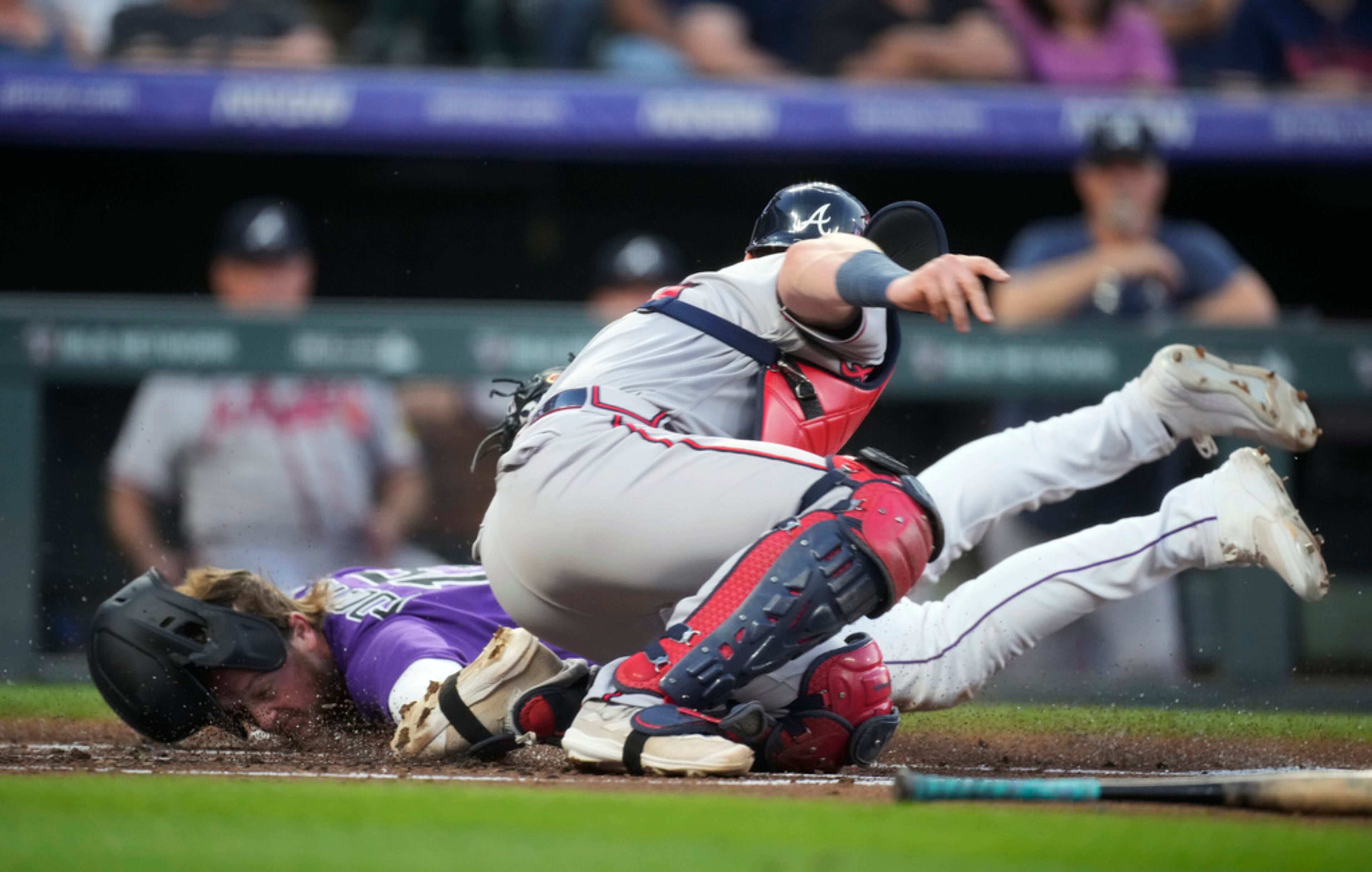 Colorado Rockies' Hunter Goodman, left, avoids the tag by Atlanta Braves catcher Sean Murphy to score during the second inning of a baseball game Tuesday, Aug. 29, 2023, in Denver. (AP Photo/David Zalubowski)
