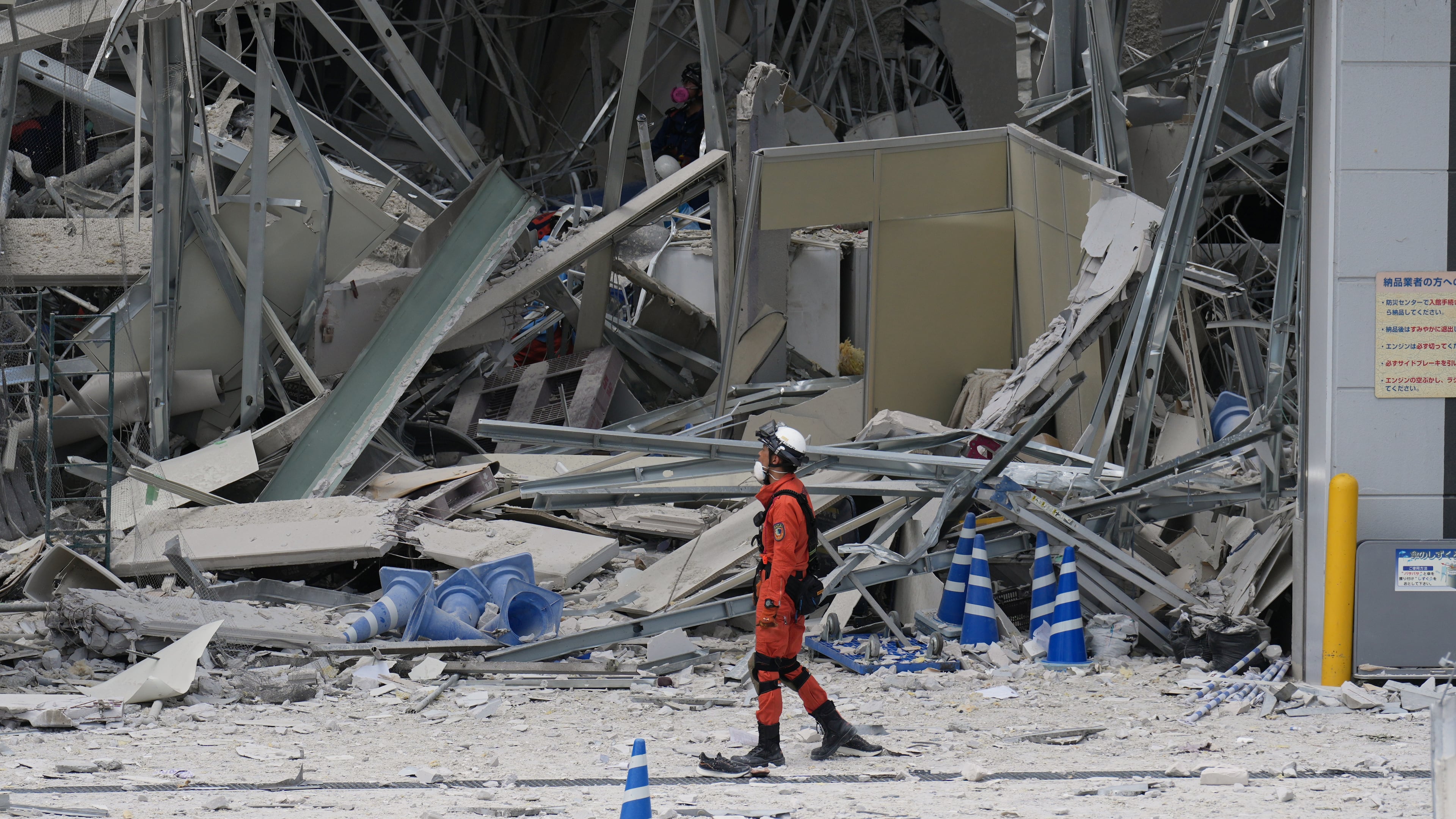A rescue worker walks in front of AEON Mall, which was damaged by an explosion following an earthquake, is seen in Kashima, Kumamoto Prefecture, southern Japan, Wednesday, July 29, 2026. (AP Photo/Hiro Komae)