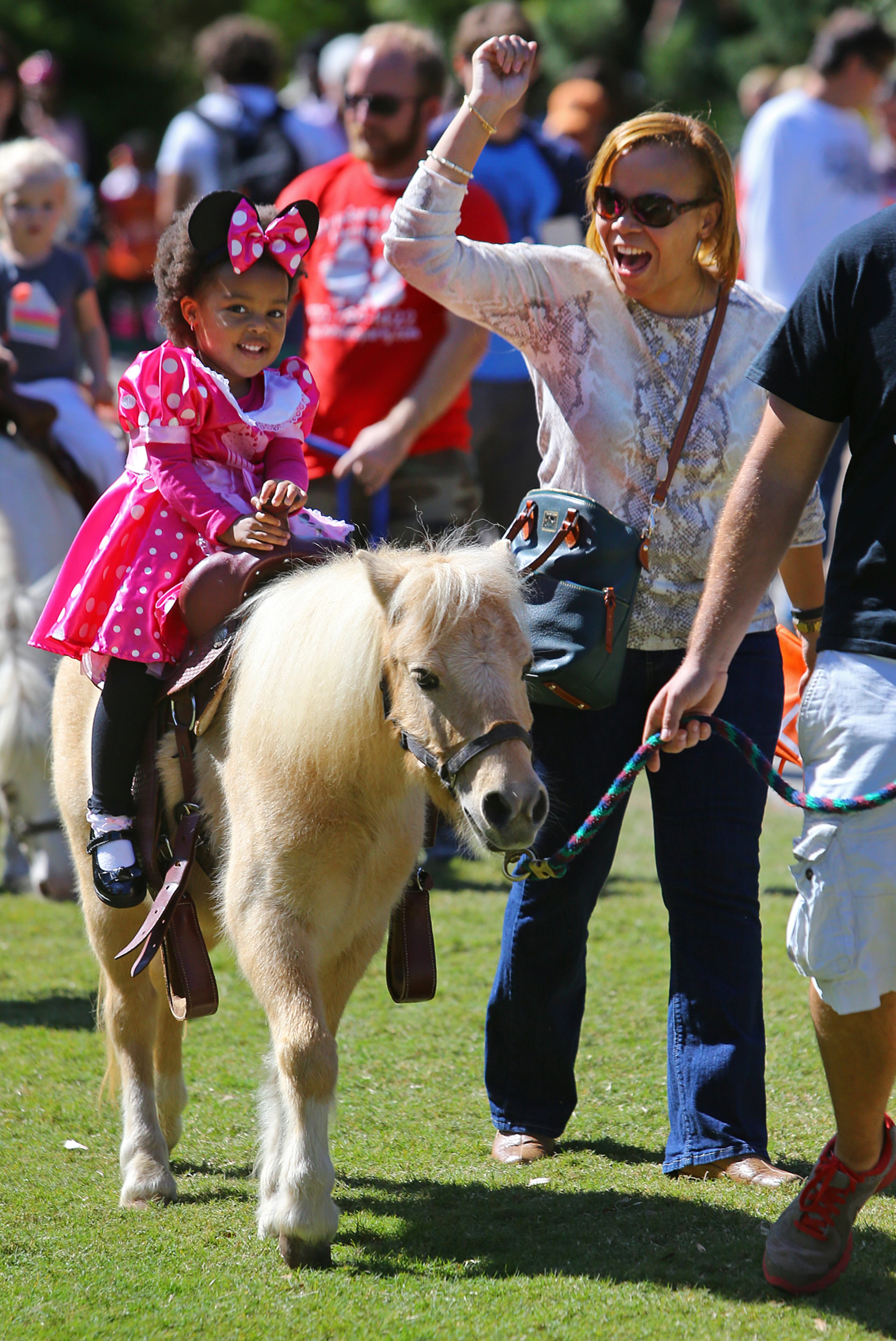 Ikenia Williams, Mableton, cheers on her 3-year-old daughter Saniya, dressed up like Minnie Mouse, while she takes a pony ride at Atlanta Botanical Gardens on Sunday, Oct. 19, 2014, in Atlanta. CURTIS COMPTON / CCOMPTON@AJC.COM