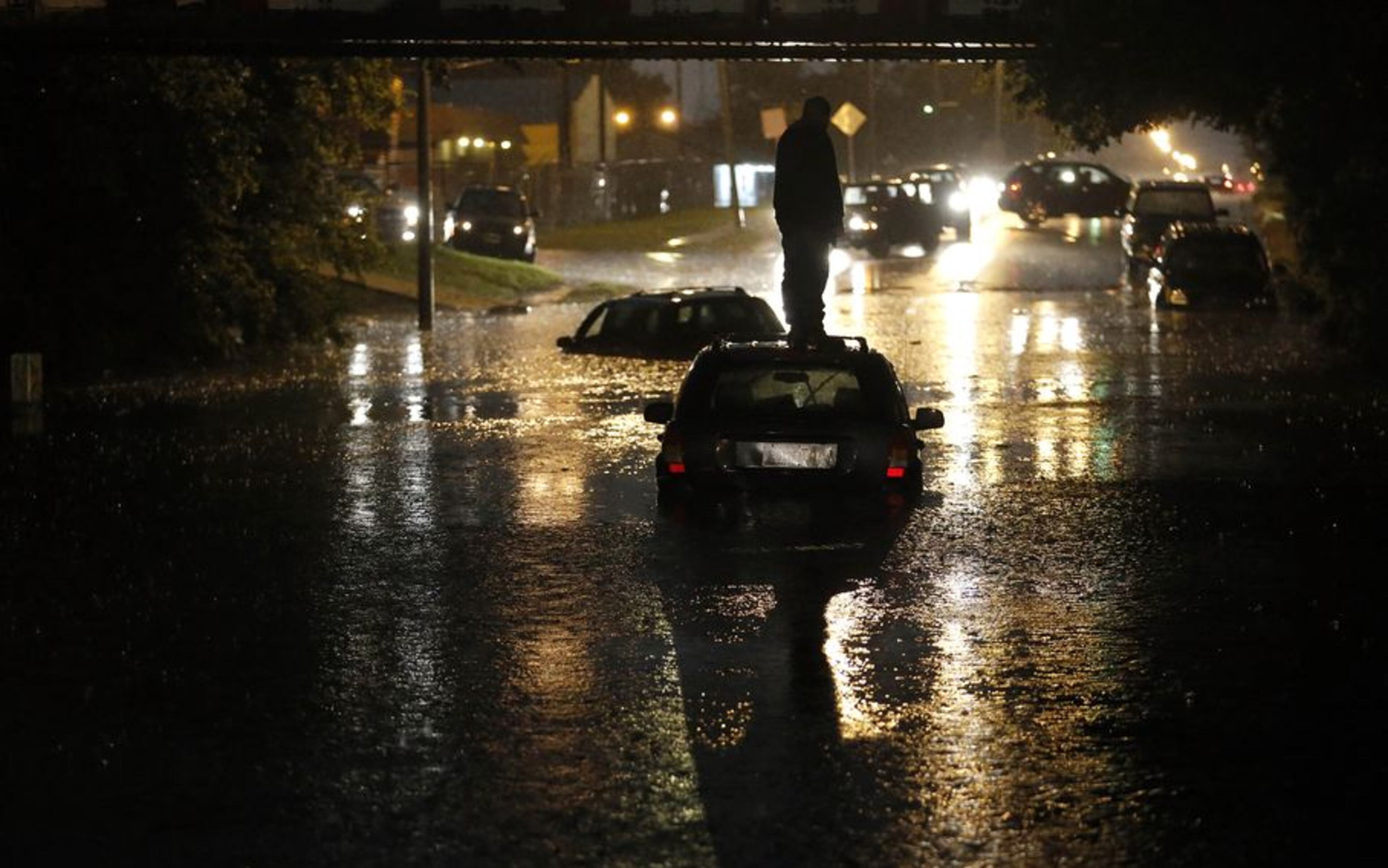 A man stands on top of his car as it is flooded on S. May Ave near SW 25th in Oklahoma City, Friday, May 31, 2013, following flooding after a severe thunderstorm moved through Oklahoma CIty. (AP Photo/The Oklahoman, Sarah Phipps)