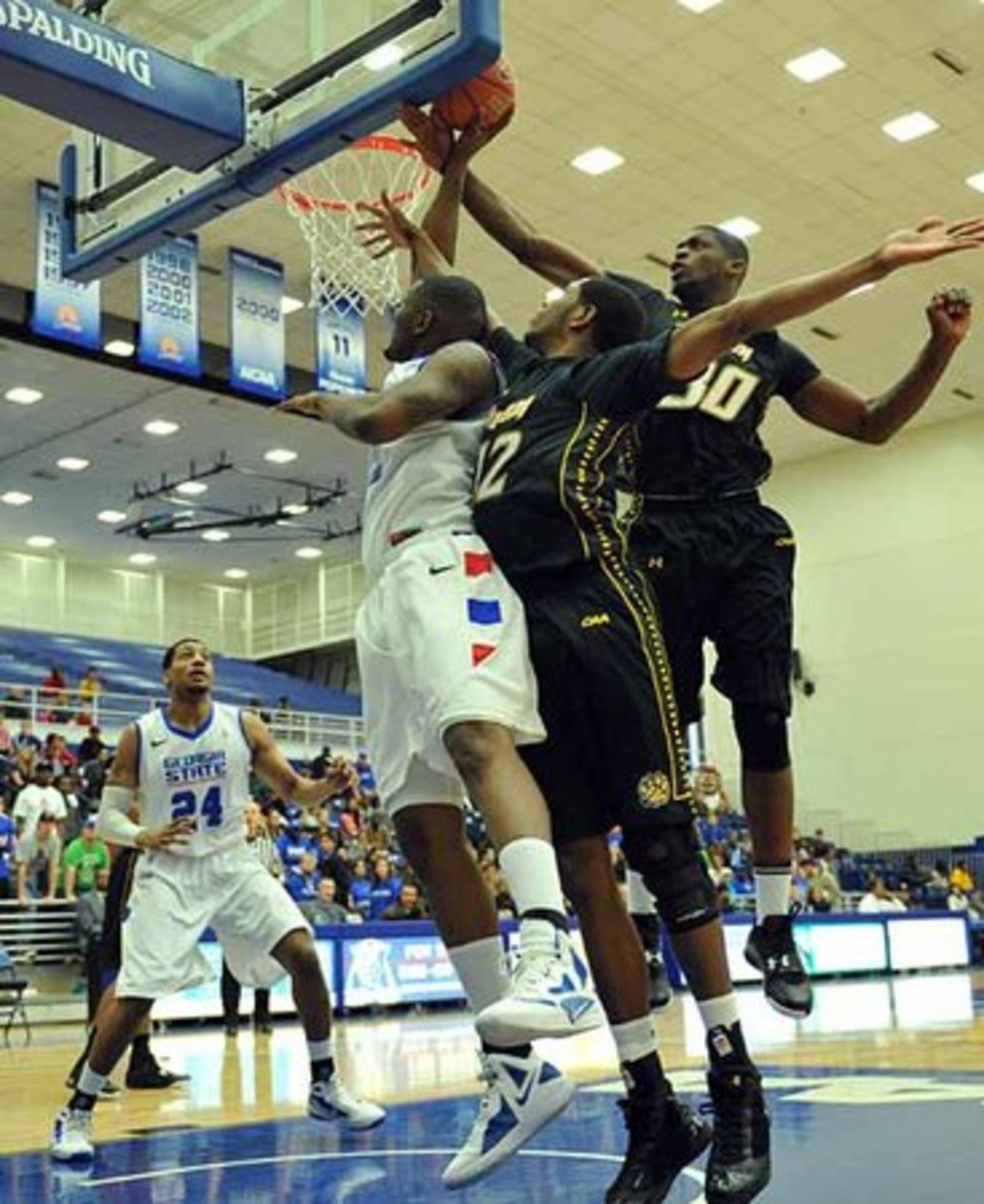 Vincent (left) is fouled by Towson forward Jervon Pressley (right) as Towson forward Erique Gumbs (center) defends.