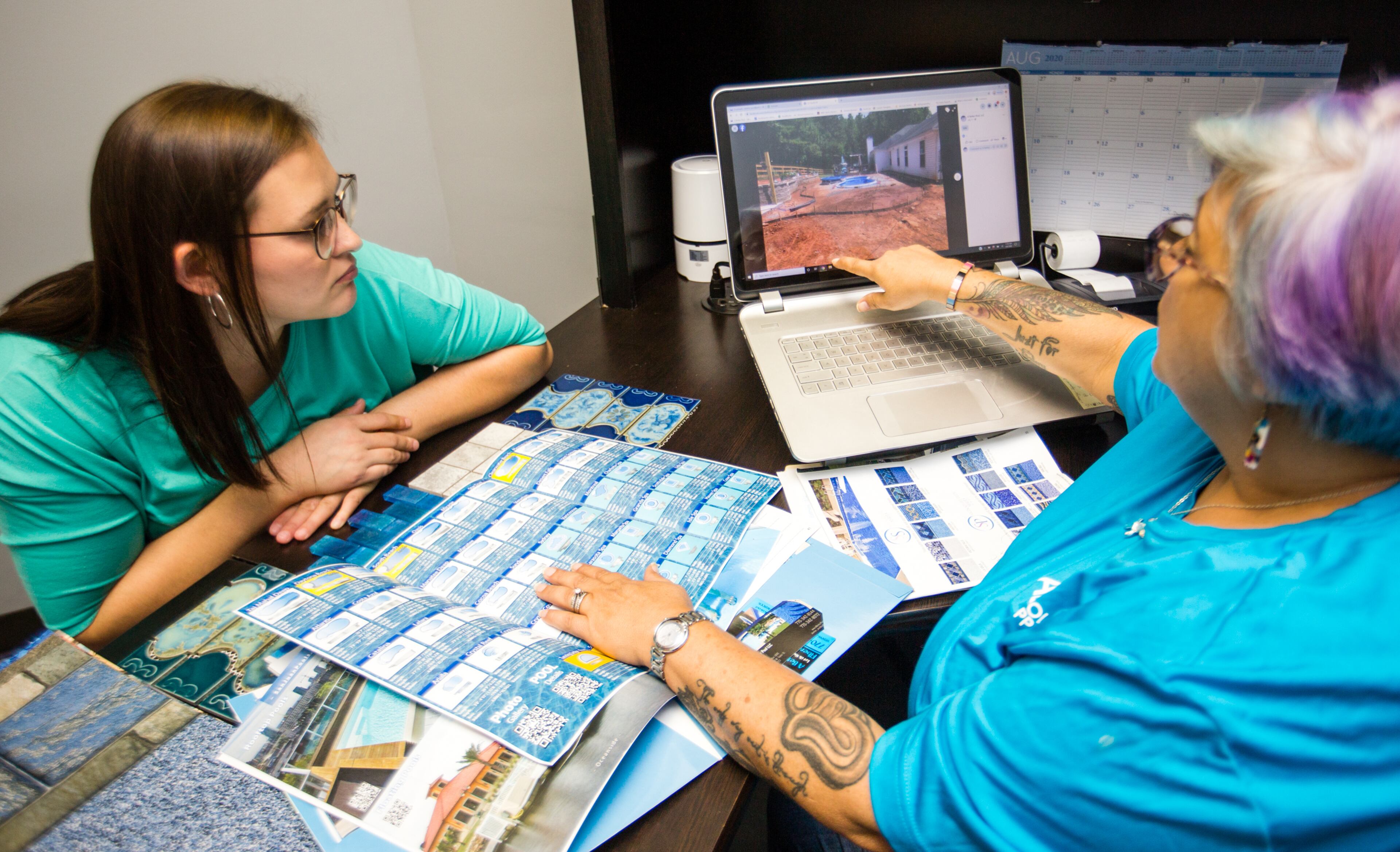 ABP Pool Supply is doing better than expected building new swimming pools and providing supplies for pool owner. DeeAnne Tallman, left, and Tammy Tallman, right, look over recent projects in the sales office where they have five contracts for new swimming pools signed in the past 10 days. (Jenni Girtman for The Atlanta Journal-Constitution)