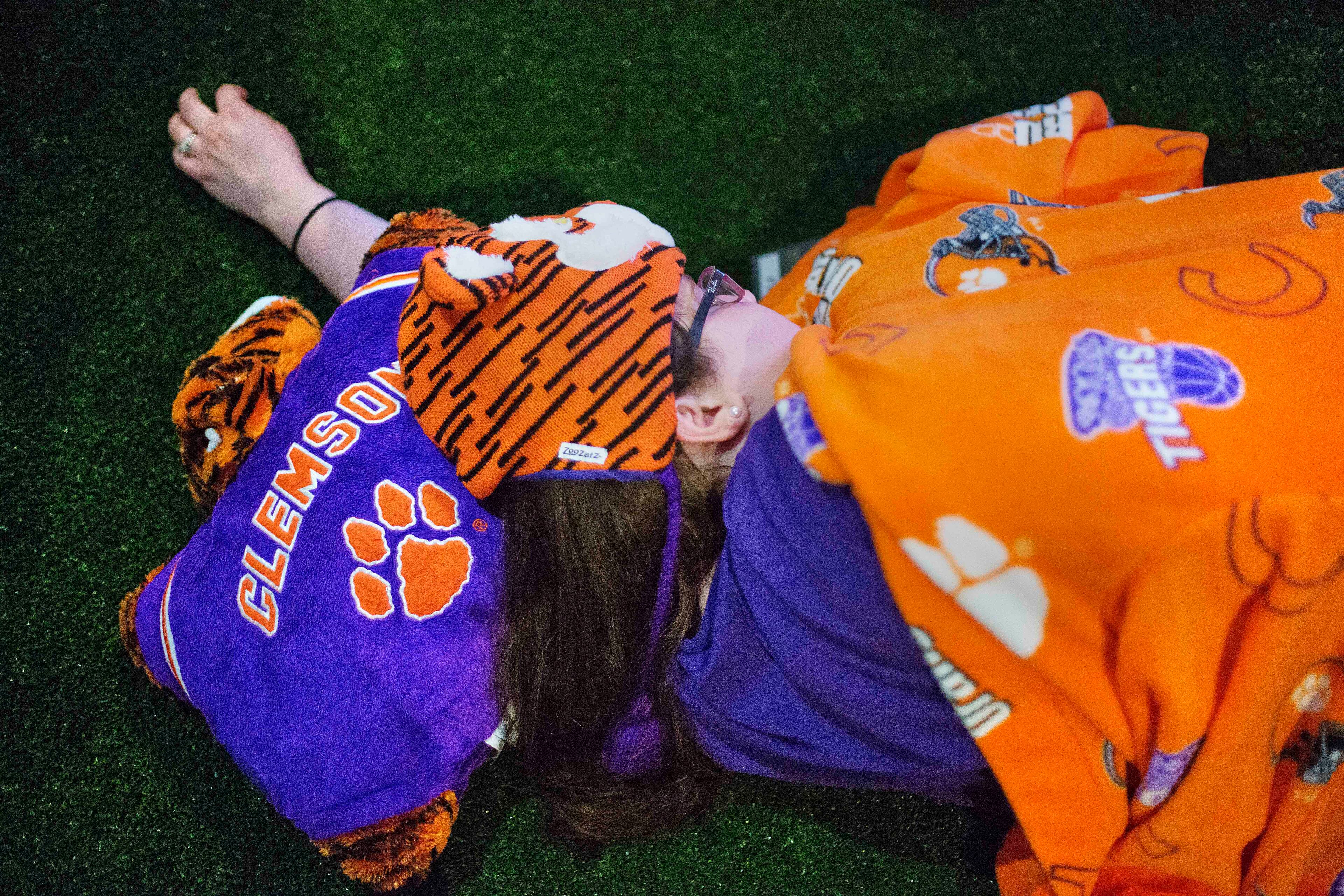 Amelia Stefanelli, of Greenville, S.C. sleeps on the turf with Clemson Tigers paraphernalia during a sleepover in the College Football Hall of Fame, Wednesday, Aug. 13, 2014, in Atlanta. One hundred contest winners who wrote an essay detailing their love of college football were selected to stay with a guest overnight in Atlanta�s College Football Hall of Fame before its grand opening and win a year�s supply of Chick-fil-A. (AP Photo/David Goldman)