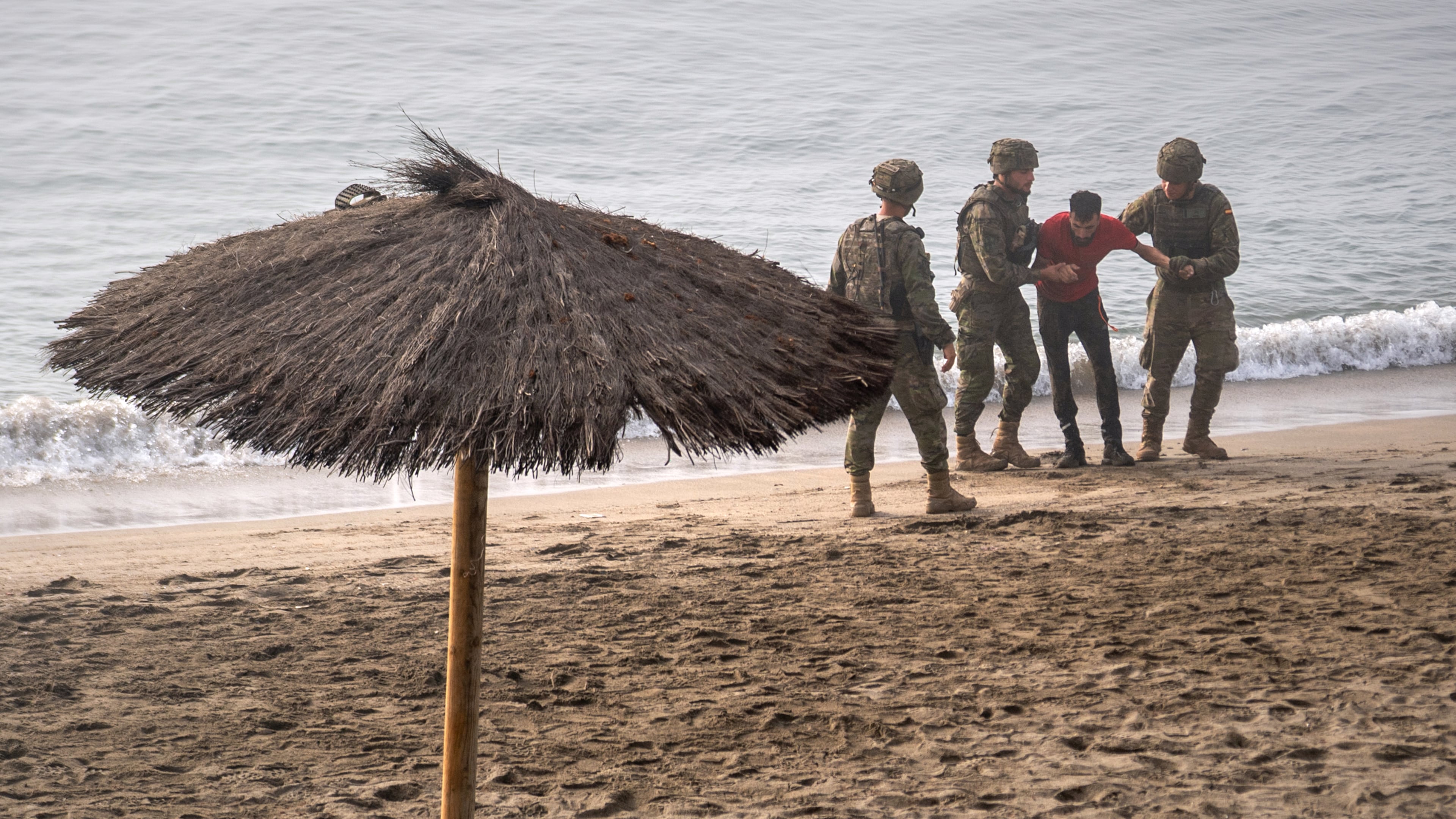 Spanish army soldiers assist a migrant who swam from Morocco to the Spanish enclave of Ceuta, Saturday, Aug. 1, 2026. (AP Photo/Antonio Sempere)