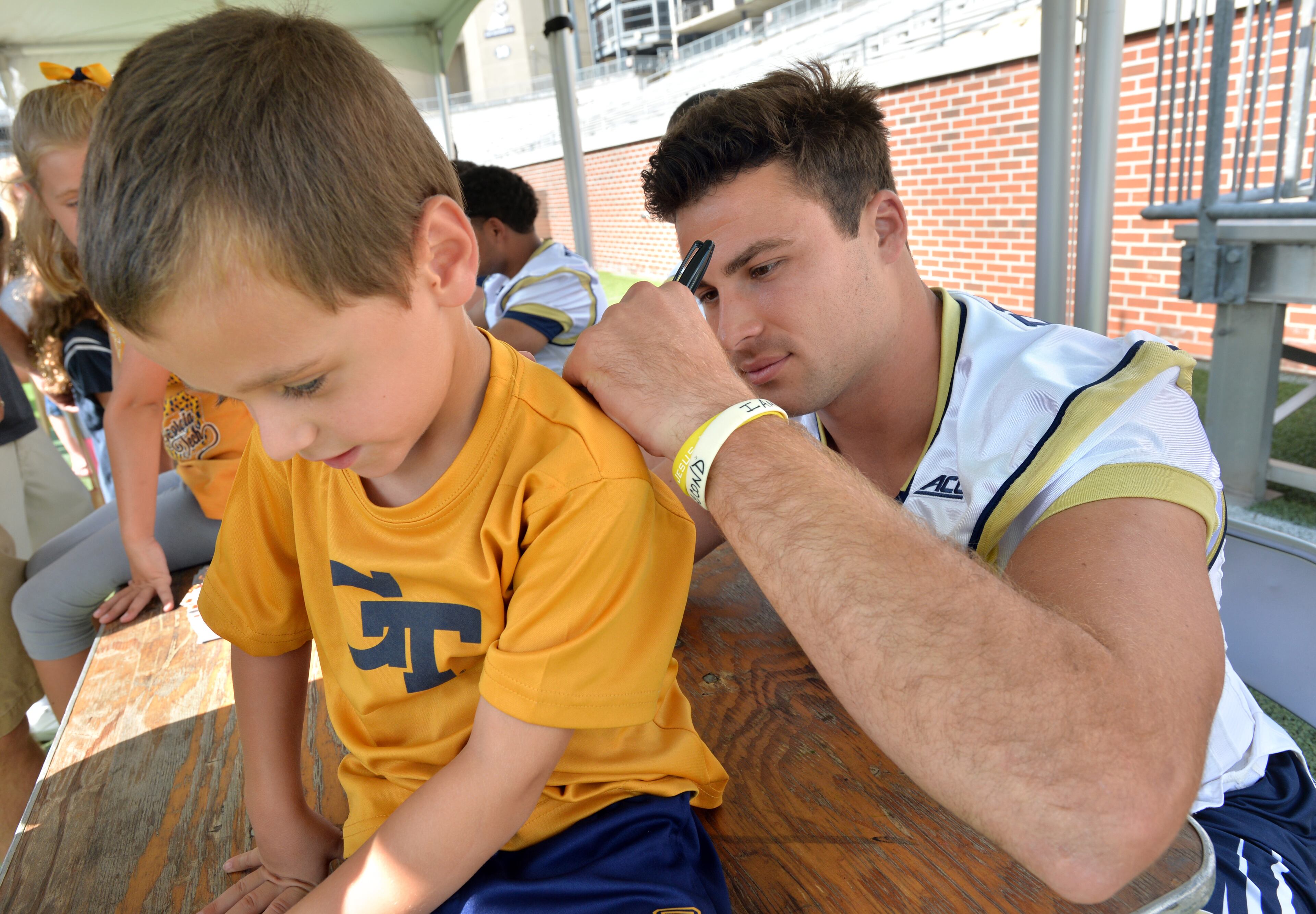 Georgia Tech quarterback Tim Byerly (18) gives Drew Cribb, 4, an autograph during Georgia Tech's annual fan day at Bobby Dodd Stadium on Saturday, August 2, 2014.