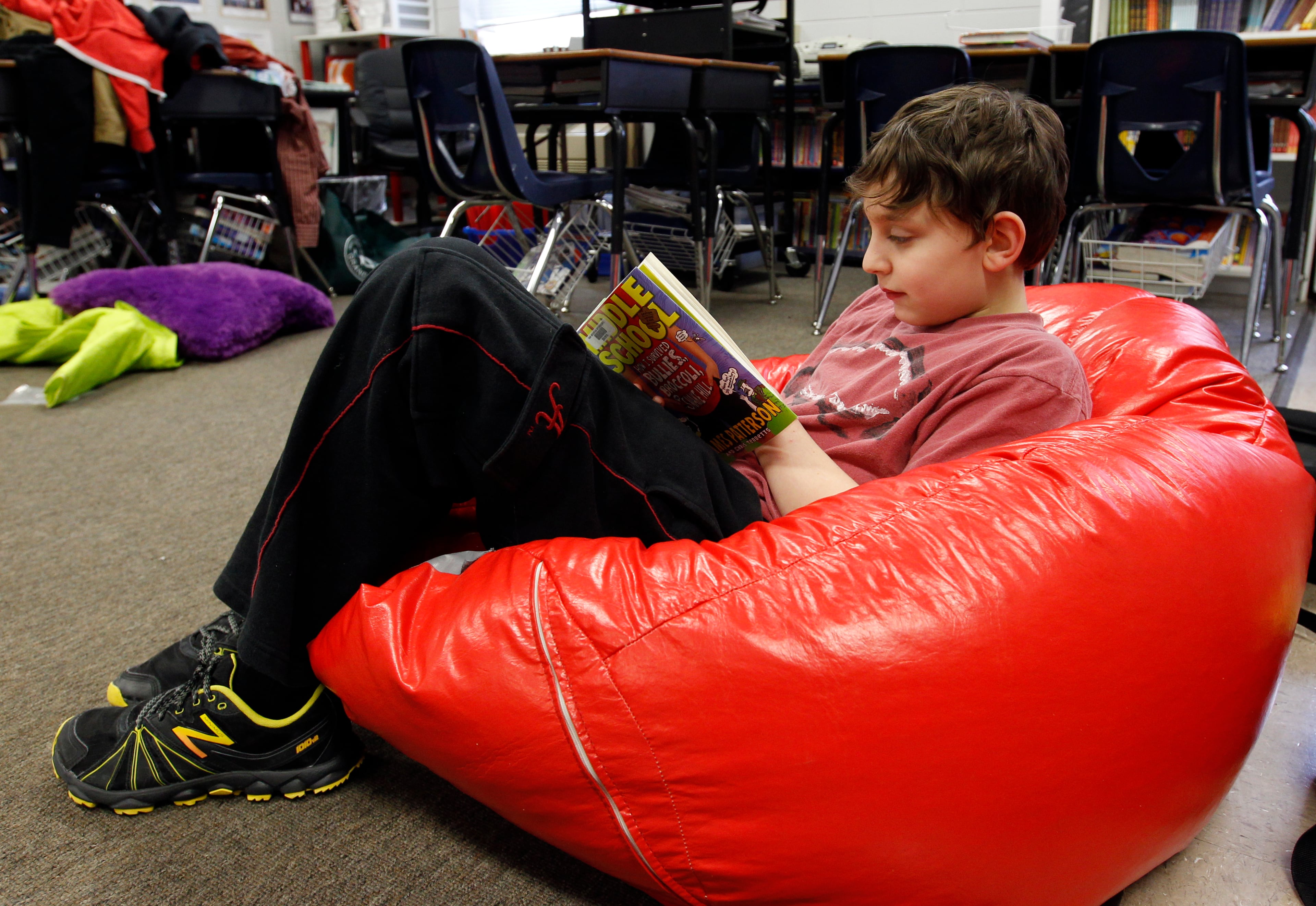 Christopher Boothby reads a book while relaxing in a bean bag chair at Oak Mountain Intermediate school on Wednesday, Jan. 29, 2014, in Indian Springs, Ala. About 80 children and 20 adults spent the night at the school due to a winter storm. Overnight, the South saw fatal crashes and hundreds of fender-benders. Jackknifed 18-wheelers littered Interstate 65 in central Alabama. (AP Photo/Butch Dill)