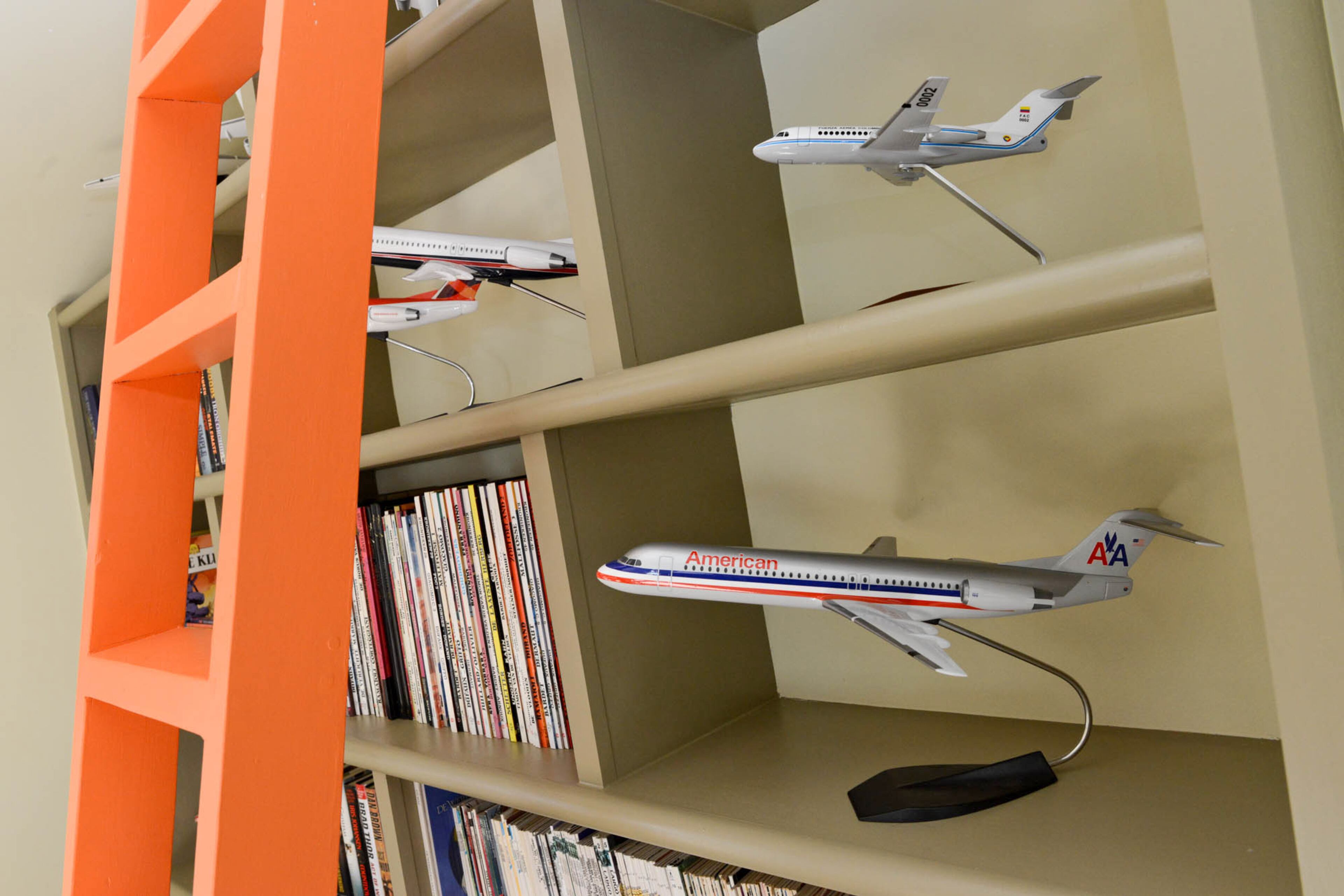 The model airplanes on display throughout the office were collected by Kouters, who works for aerospace company Fokker Services. Like many other pieces throughout their home, this collection is a personal touch that can't be replicated. The orange ladder pops against the floor-to-ceiling shelves.