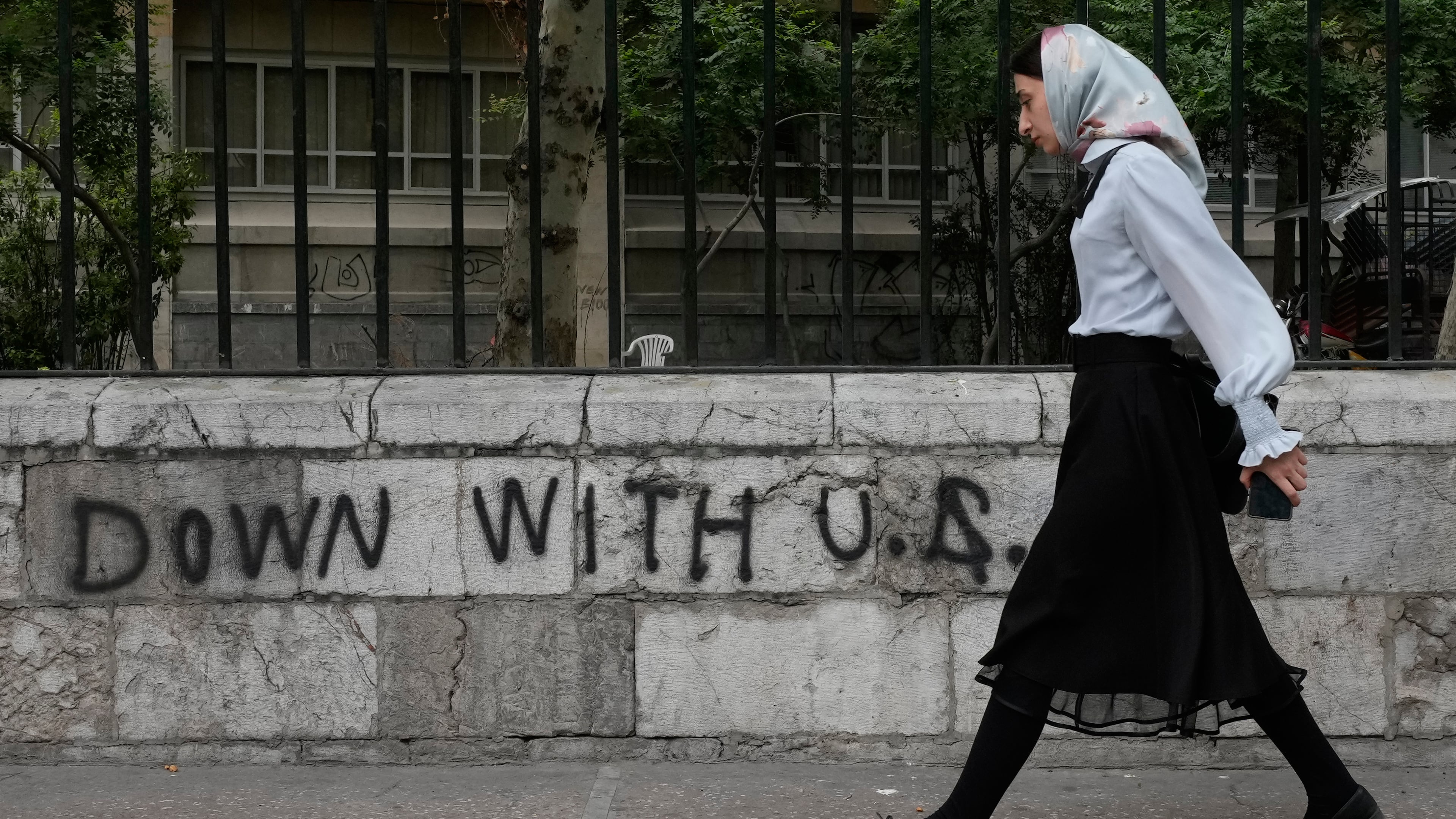 A woman walks past an anti-U.S. graffiti painted on the wall of the Tehran University on Enqelab-e-Eslami (Islamic Revolution) street in downtown Tehran, Iran, Saturday, April 25, 2026. (AP Photo/Vahid Salemi)