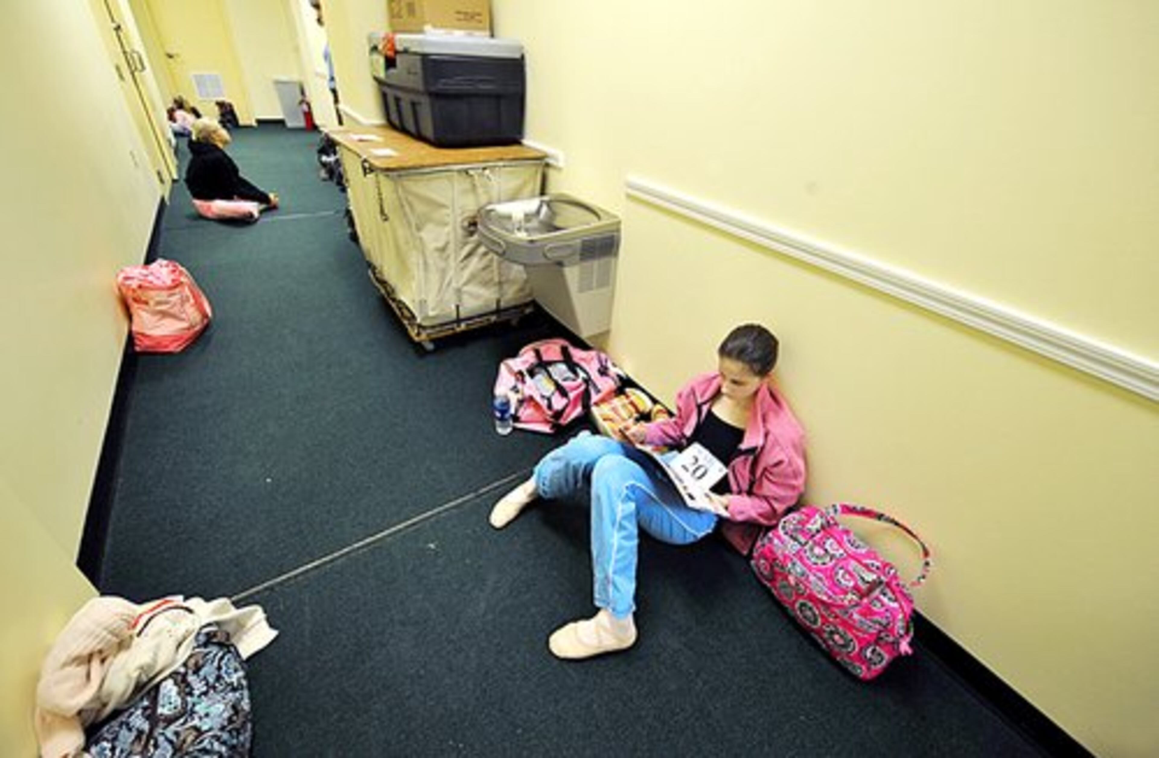 Emma Clinch, 13, of Dunwoody, rests in the hallway before being called for auditions.