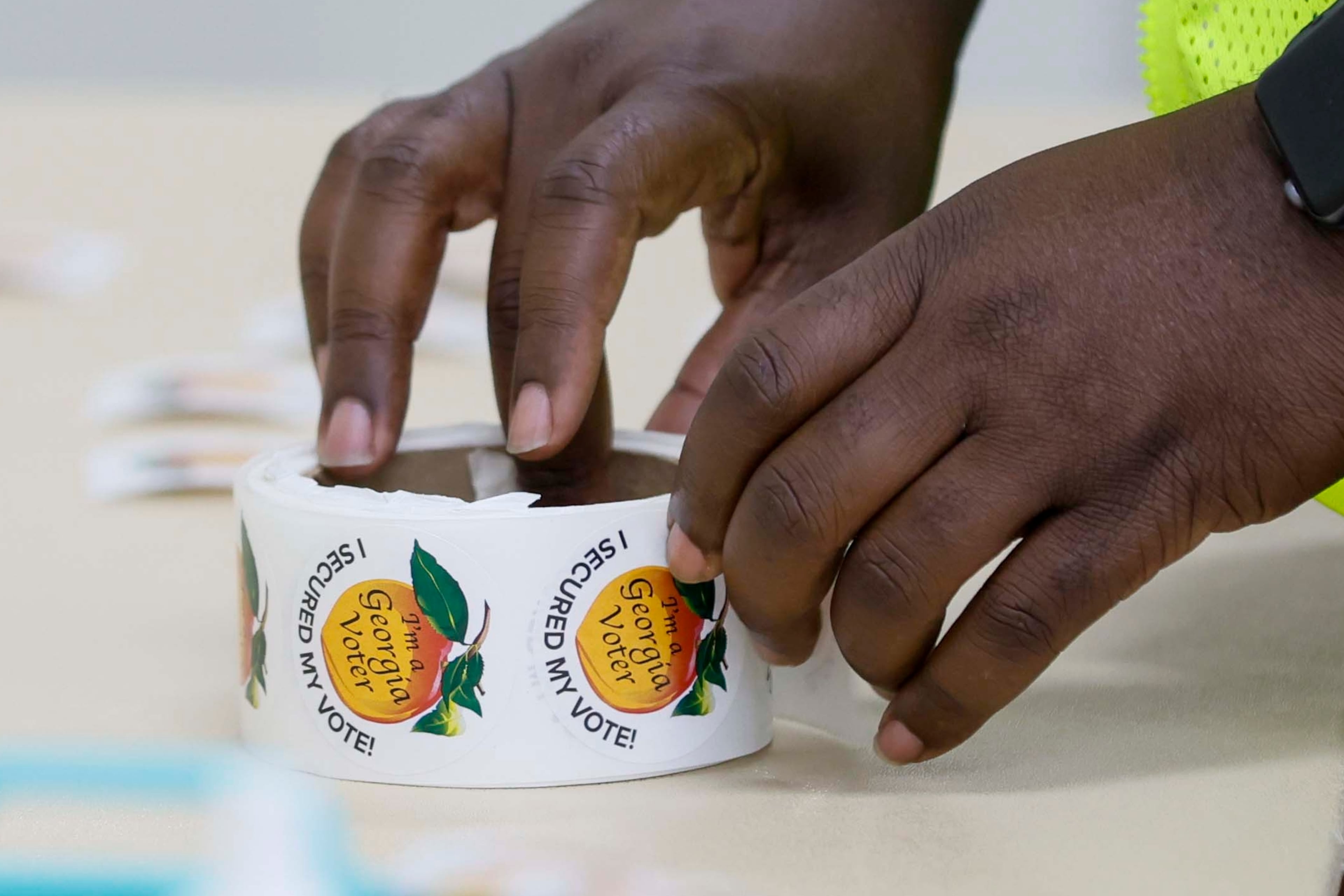 A poll worker readies voter stickers for distribution at the Ron Anderson Community Center in Powder Springs, Ga. last year. (Miguel Martinez/AJC 2025)