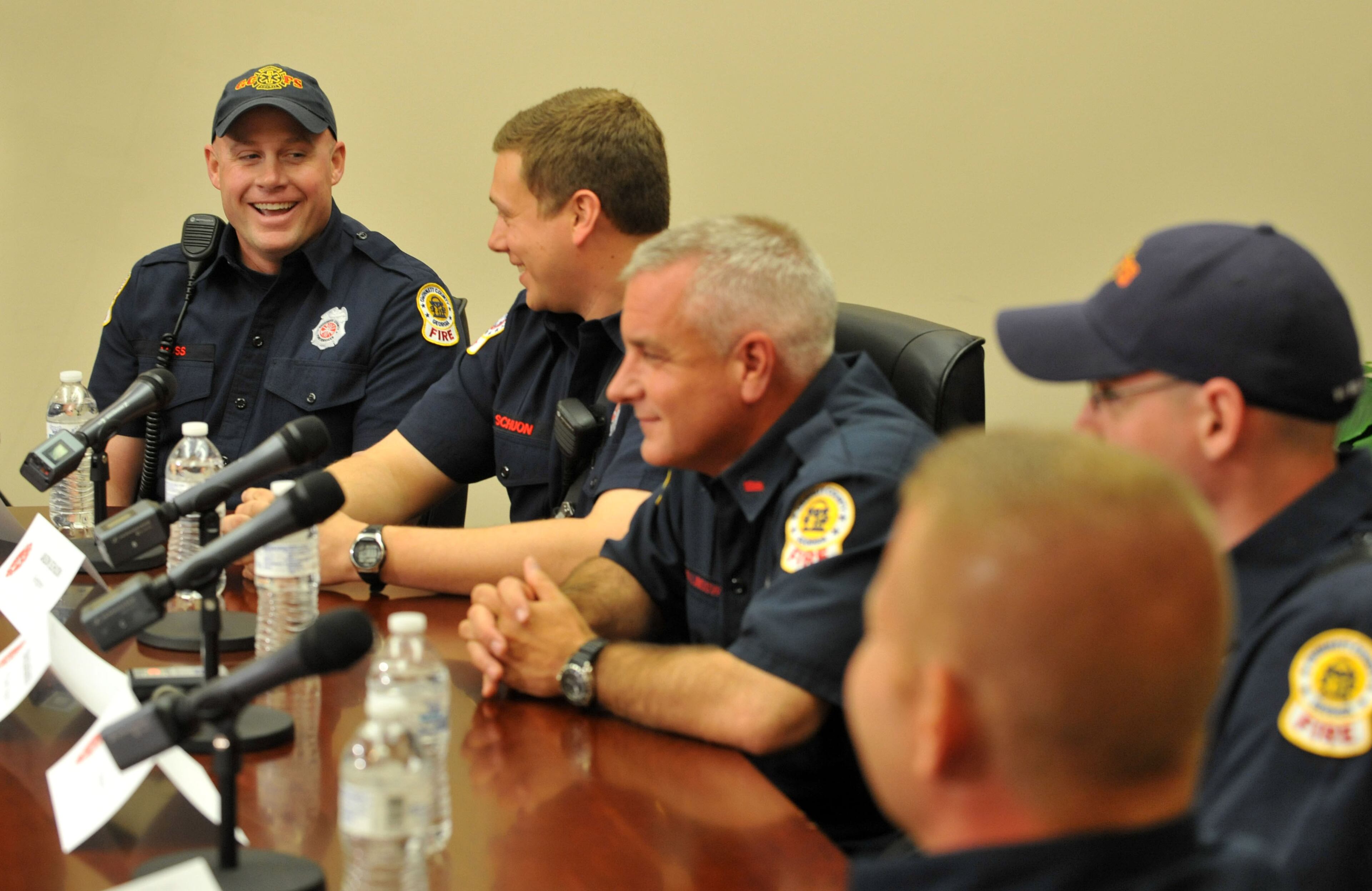 Firefighter Jody Moss(left) , describes how they tried to lighten the mood with the guman as the the rest of the crew reacts. Firefighter Jason Schuon, (2nd from left), Tim Hollingsworth, Chip Echols, and Sidney Garner, 4 years, during the press conference.