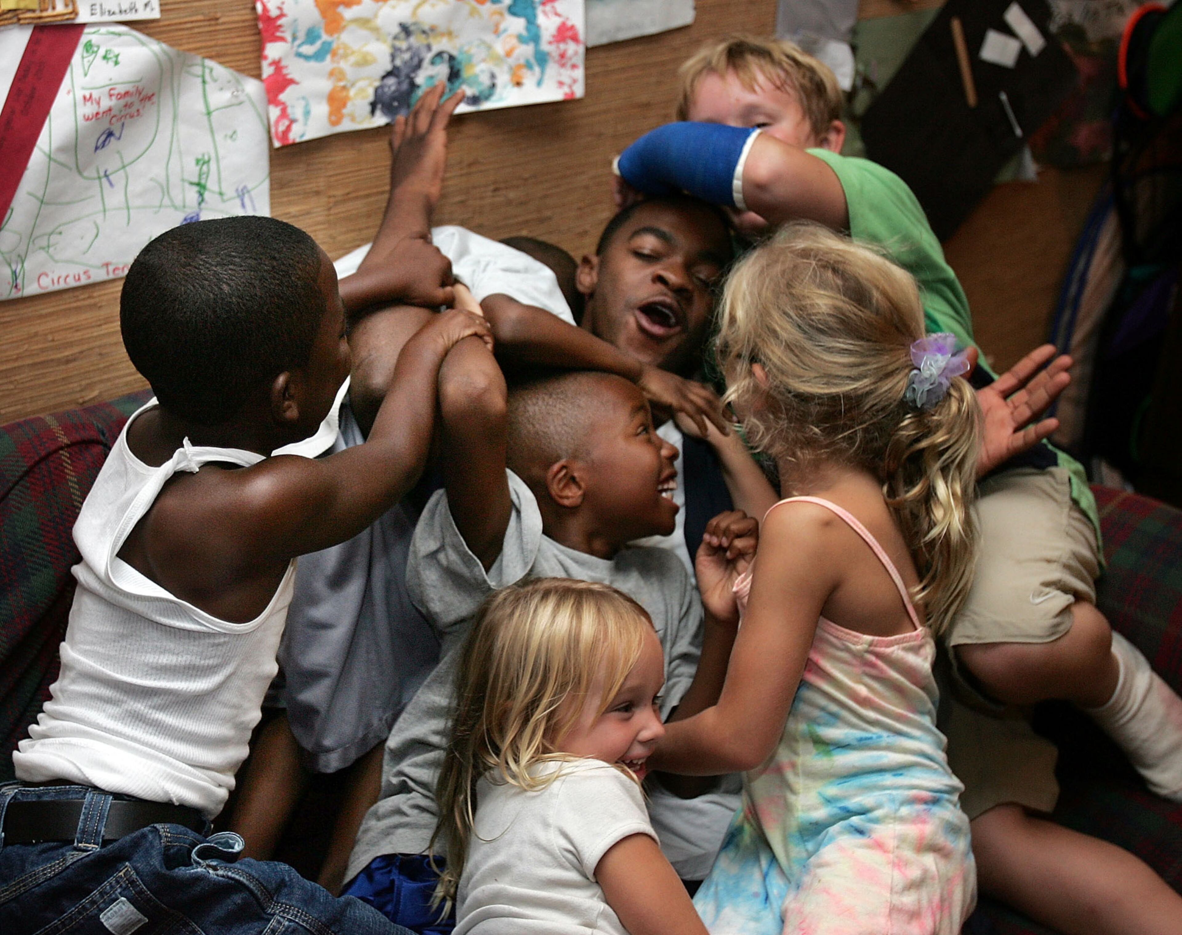 050908- Darrell Singleton (center, back) gets mobbed by kids, including (L to R) Tyron Celestine, Lawson Celestine, Bryson Celestine (obscurred), and Carleigh, Elizabeth and Dalton Moore while horsing around after having a group photo taken with the kids. Carol and Boake Moore of Roswell have 4 children and a house in Roswell and have taken in a group of evacuees from New Orleans. The children from these two different cultures are growing close, and the adults are too. BOB ANDRES/STAFF