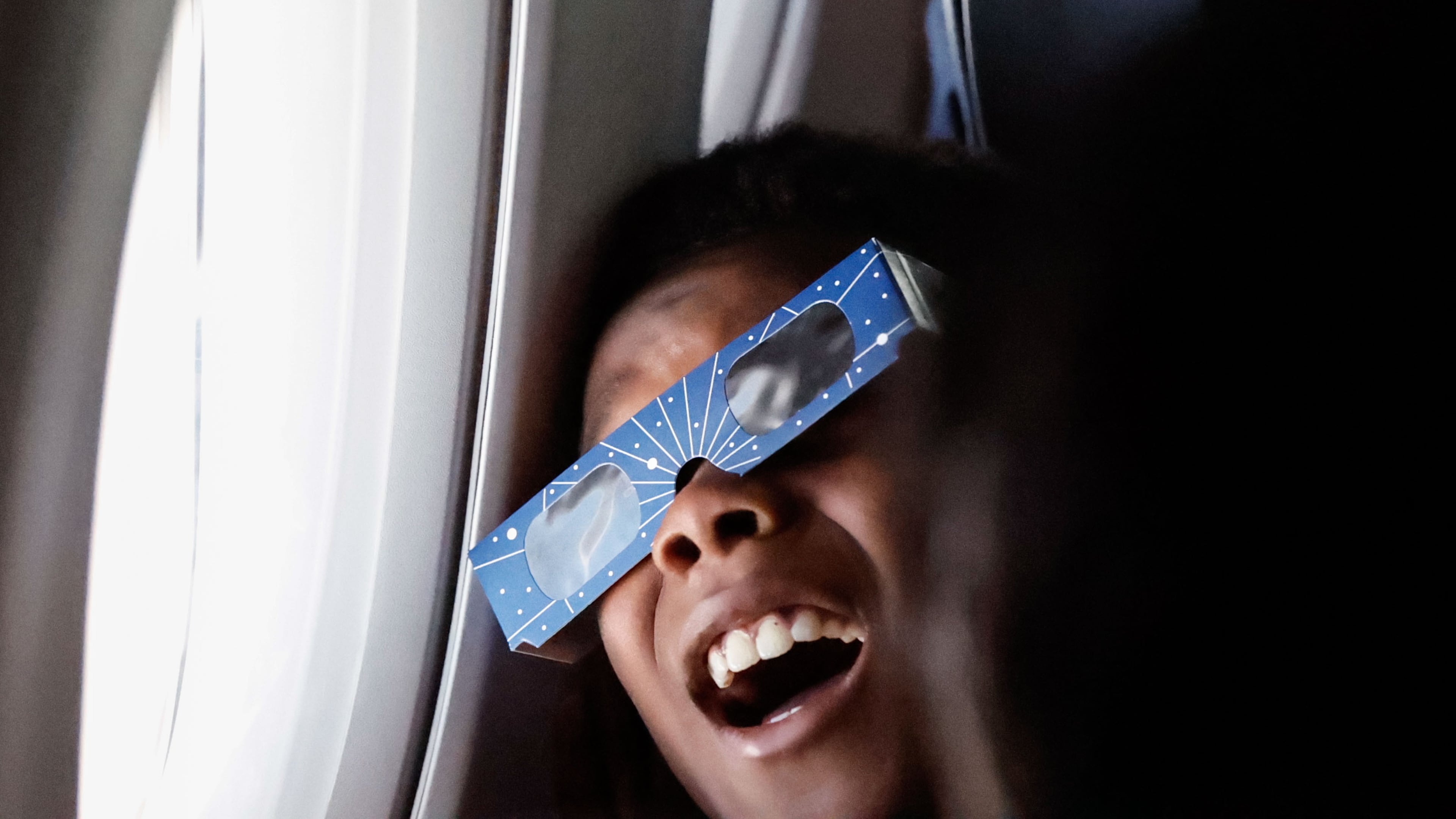 Kyle McSween, 9 from Atlanta, looks out the window during the solar eclipse on Delta Air Line’s flight along the eclipse path from Dallas to Detroit on Monday, April 8, 2024. (Natrice Miller/ Natrice.miller@ajc.com)