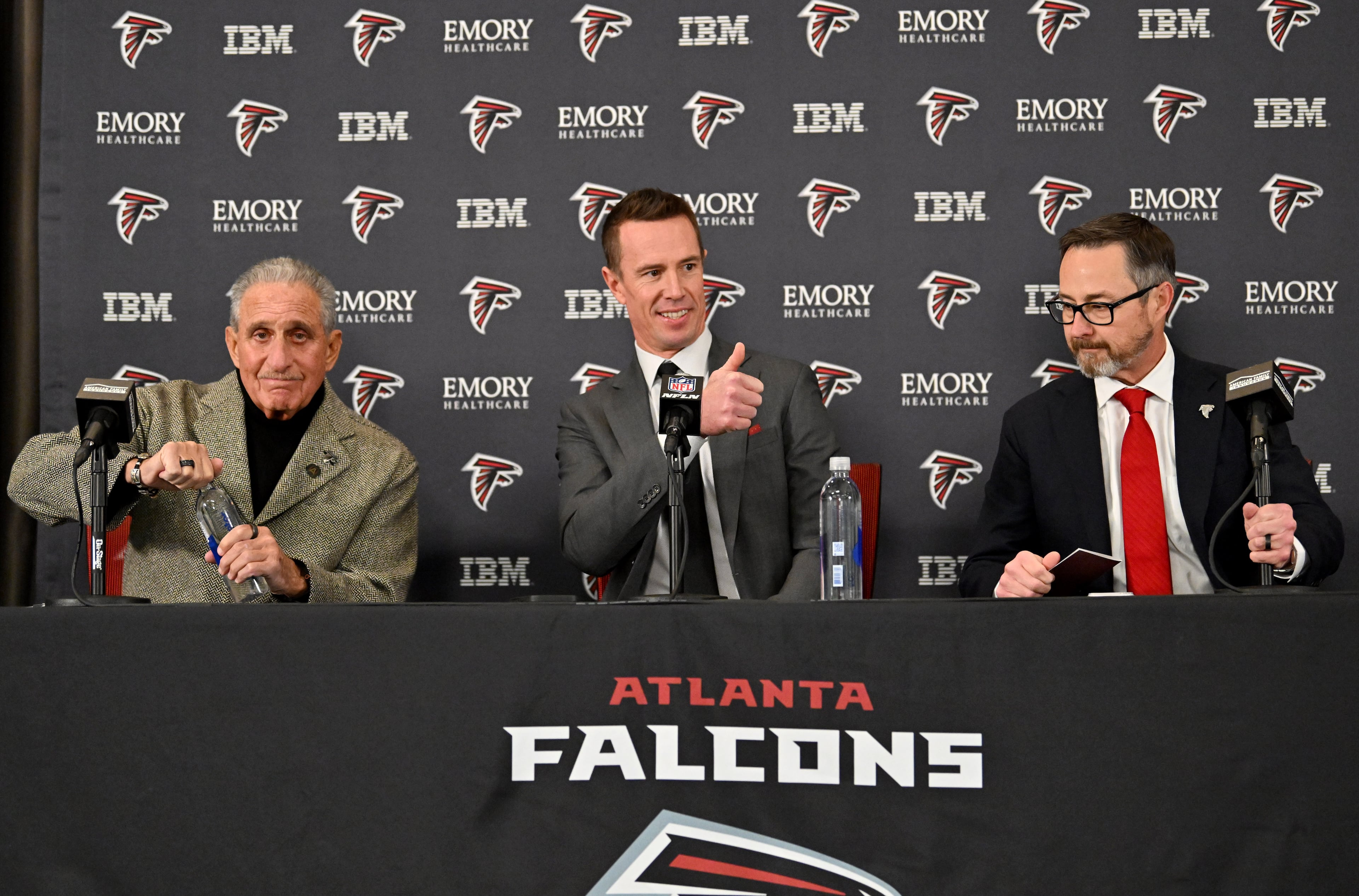 New Falcons president of football Matt Ryan gestures to his family as he enters with Arthur M. Blank (left) and CEO Greg Beadles for a news conference to introduce new Falcons president of football Matt Ryan, Tuesday, Jan. 13, 2026, in Flowery Branch. (Hyosub Shin/AJC)