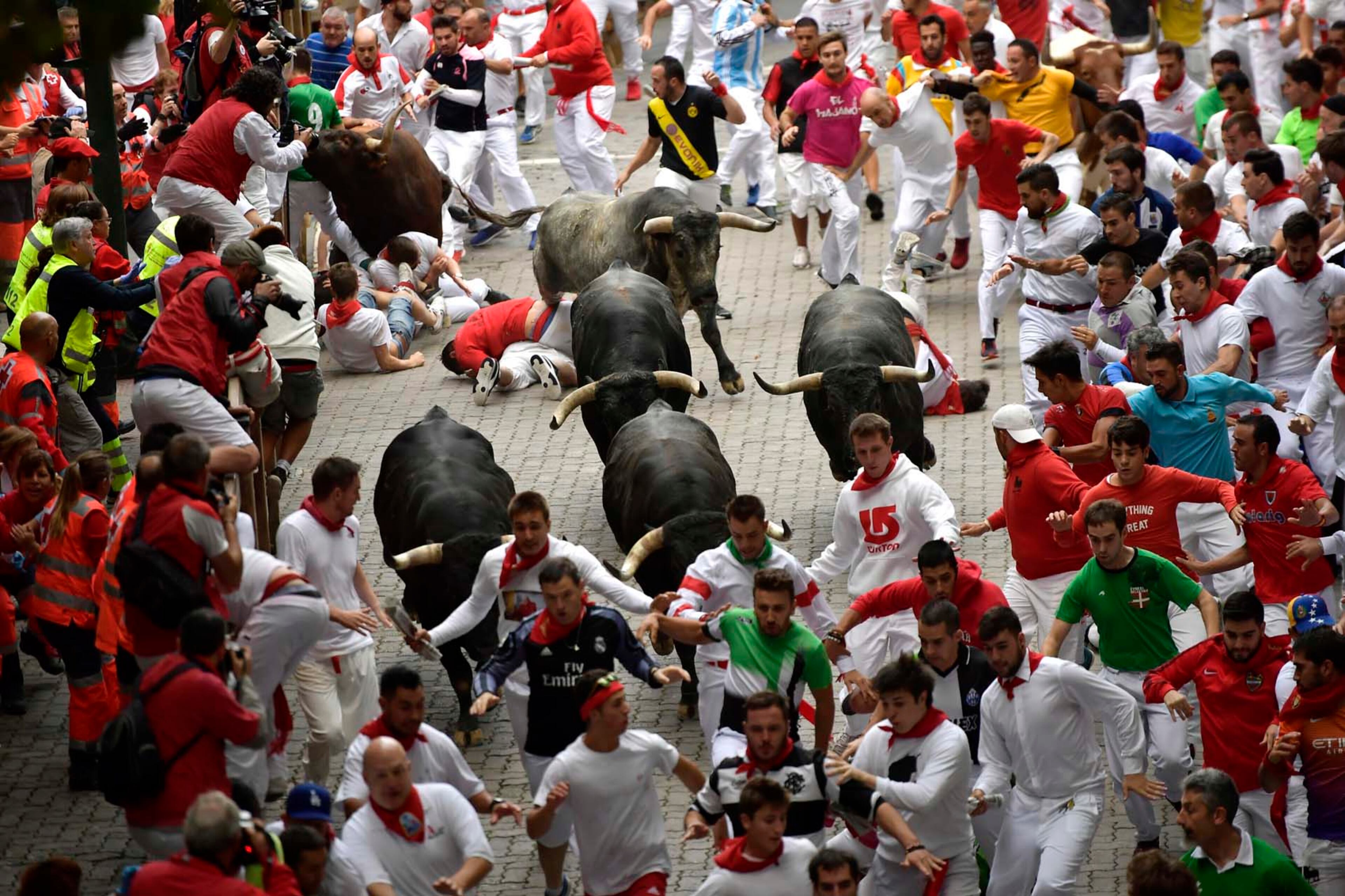 Revellers fall next to Miura's fighting bulls during the running of the bulls at the San Fermin Festival, in Pamplona, northern Spain, Friday, July 14, 2017. Medical officials in Spain say that the bull run on the final day of the San Fermin festival has left six people injured. But no gorings have been reported. (AP Photo/Alvaro Barrientos)