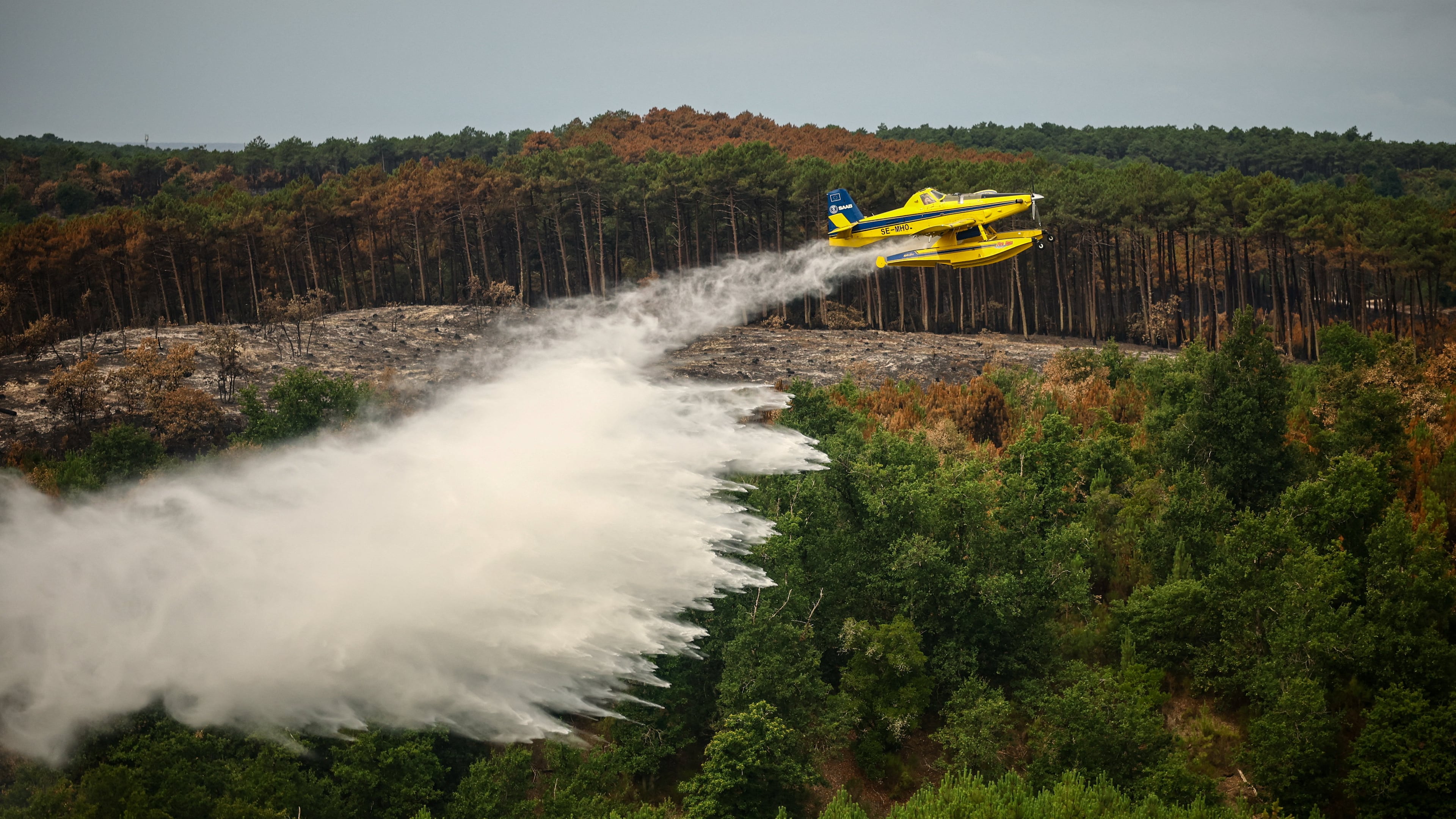 A picture taken from the French Civil Security rescue coordination helicopter shows a firefighting plane dropping water during a wildfire in Le Porge, France, Firday, July 31, 2026. (Sarah Meyssonnier/Pool Photo via AP)