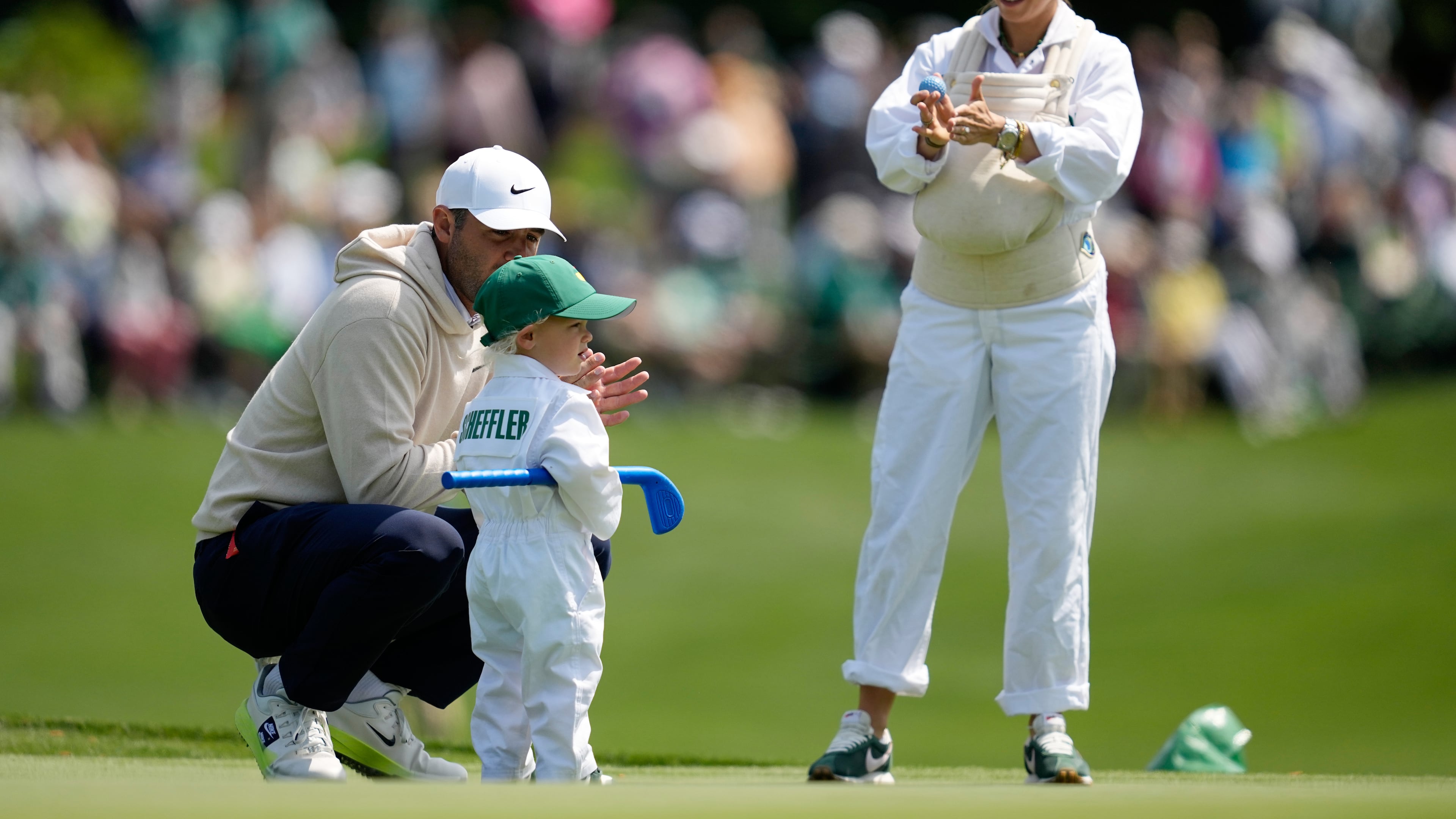 Scottie Scheffler, left, speaks with his son, Bennett, center, as his wife Meredith holds their son Remy, on the third hole during par-3 contest ahead of the Masters golf tournament at the Augusta National Golf Club, Wednesday, April 8, 2026, in Augusta, Ga. (AP Photo/Ashley Landis)