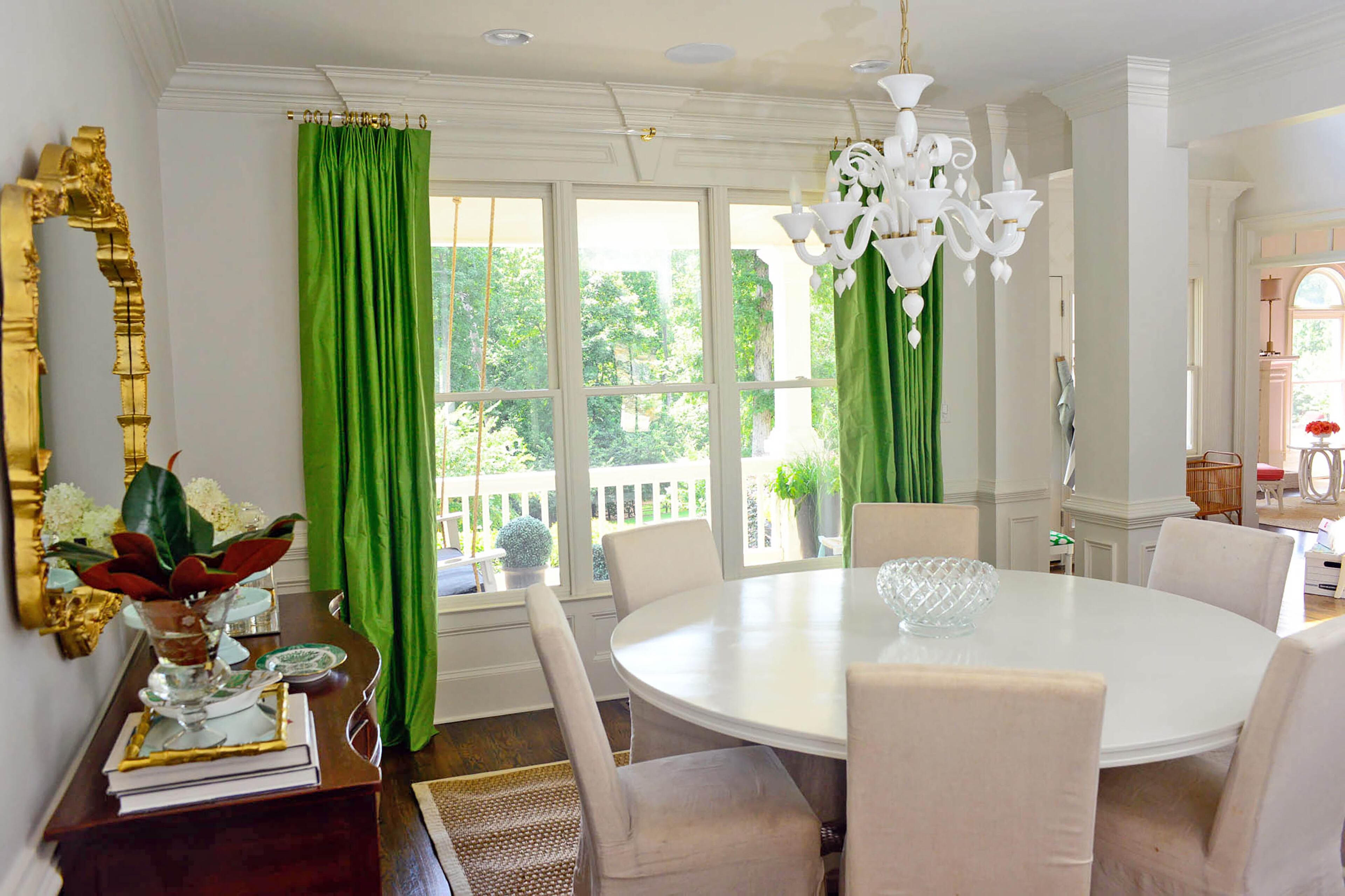 A custom dining table crafted by Carey Durbin of CD Natural Creations centers the dining room. Natural light fills the room through large windows that look out on the front porch. Combined with the white glass Treviso chandelier from Cyan Design, the windows give the room a light and airy feeling