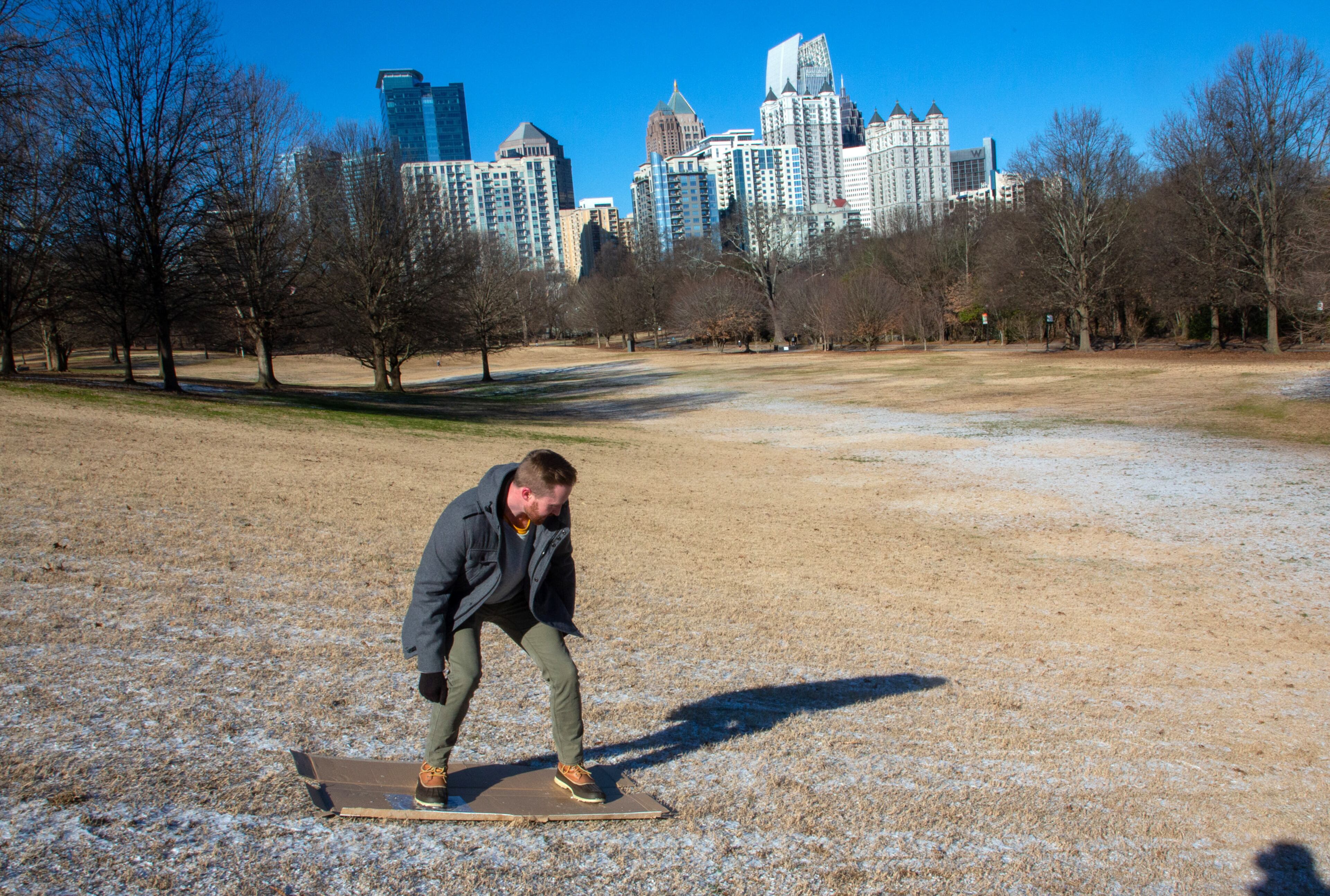 Chris Yegge slides down a snow-dusted hill on a piece of cardboard in Piedmont Park Saturday, July 29, 2022. STEVE SCHAEFER FOR THE ATLANTA JOURNAL-CONSTITUTION