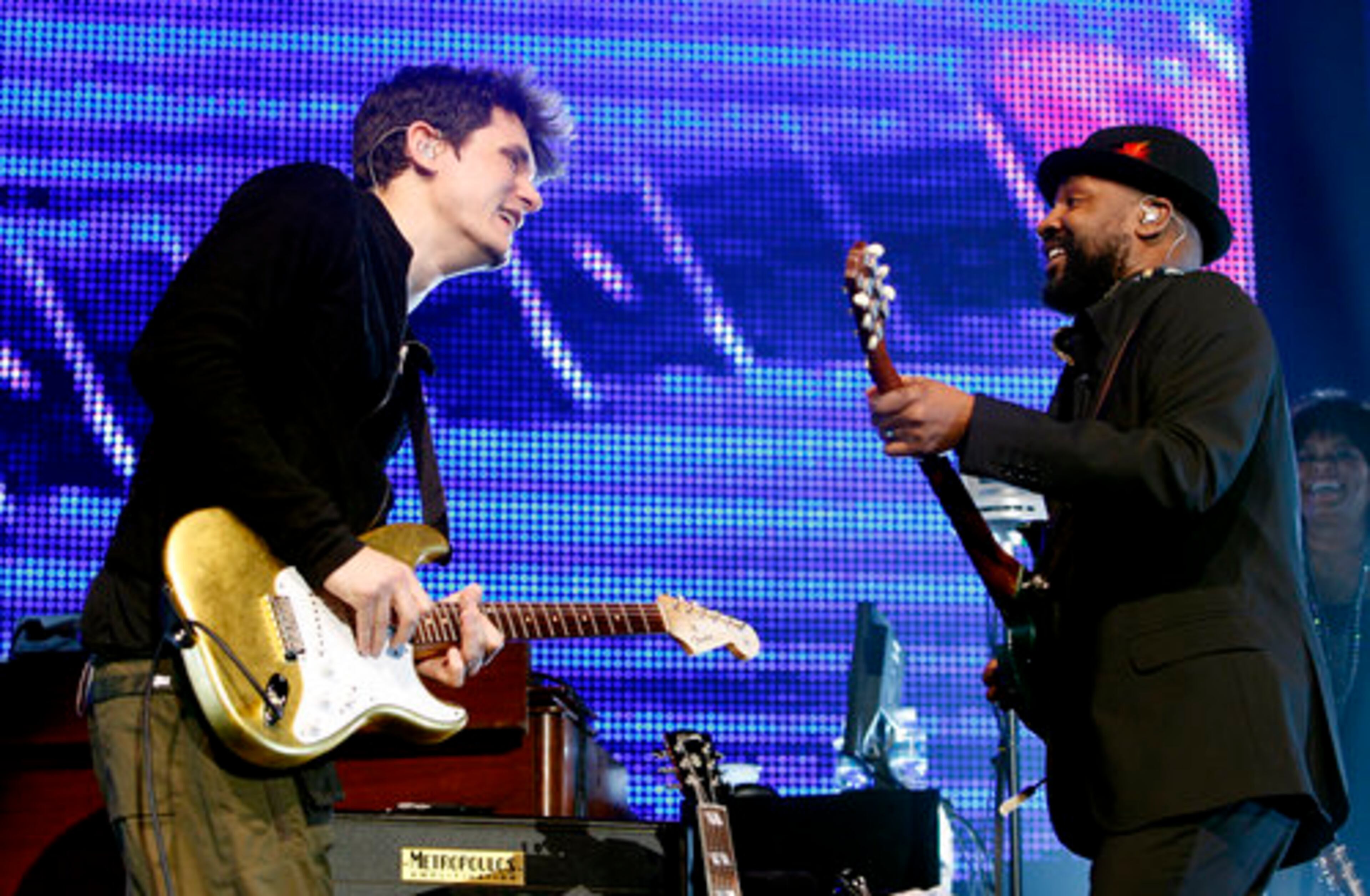 John Mayer backs away smiling at a band member after trading guitar riffs.