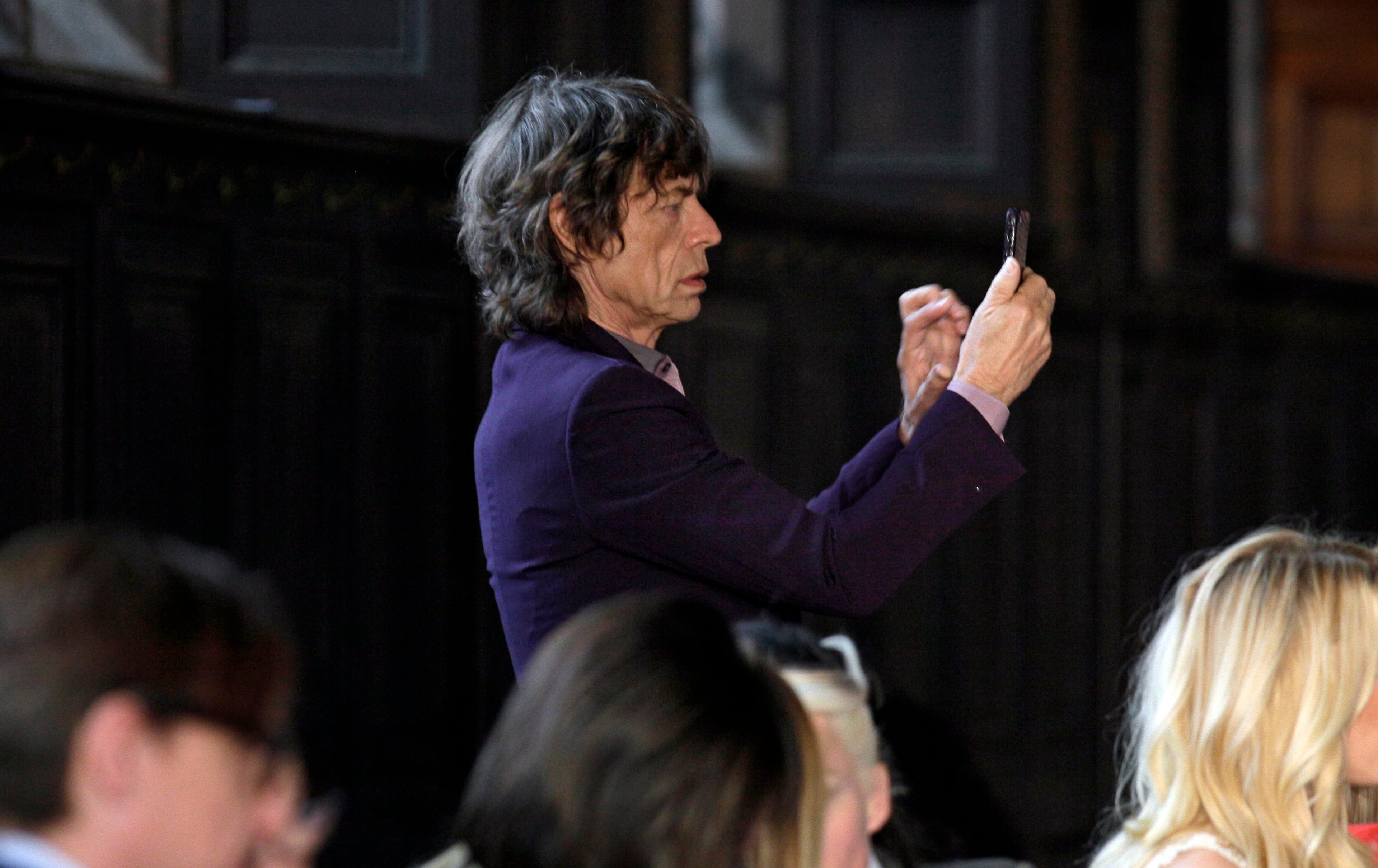'This Feb. 16, 2012 file photo shows singer Mick Jagger as he photographs designer L'Wren Scott in the finale of her Fall 2012 collection was modeled during Fashion Week, in New York. Scott was found dead Monday, March 17, 2014, in Manhattan. (AP Photo/Richard Drew, File)