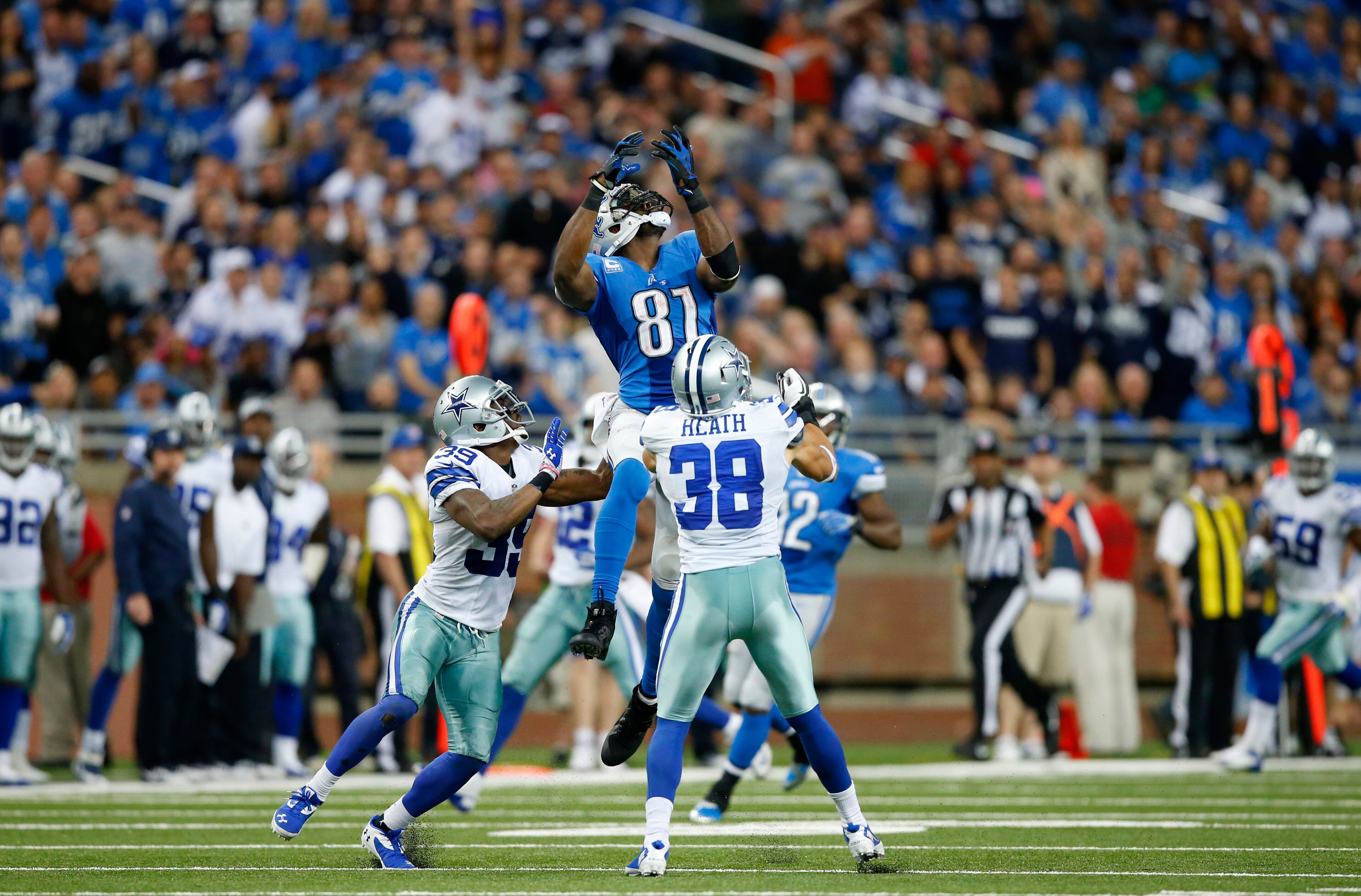 Detroit Lions wide receiver Calvin Johnson (81) catches a 54-yard reception against Dallas Cowboys cornerback Brandon Carr (39) and defensive back Jeff Heath (38) in the fourth quarter of an NFL football game in Detroit. Johnson had 329 receiving yards, the second the most in one game in NFL history. The Detroit Lions beat the Dallas Cowboys 31-30 in a classic. (AP Photo/Rick Osentoski)