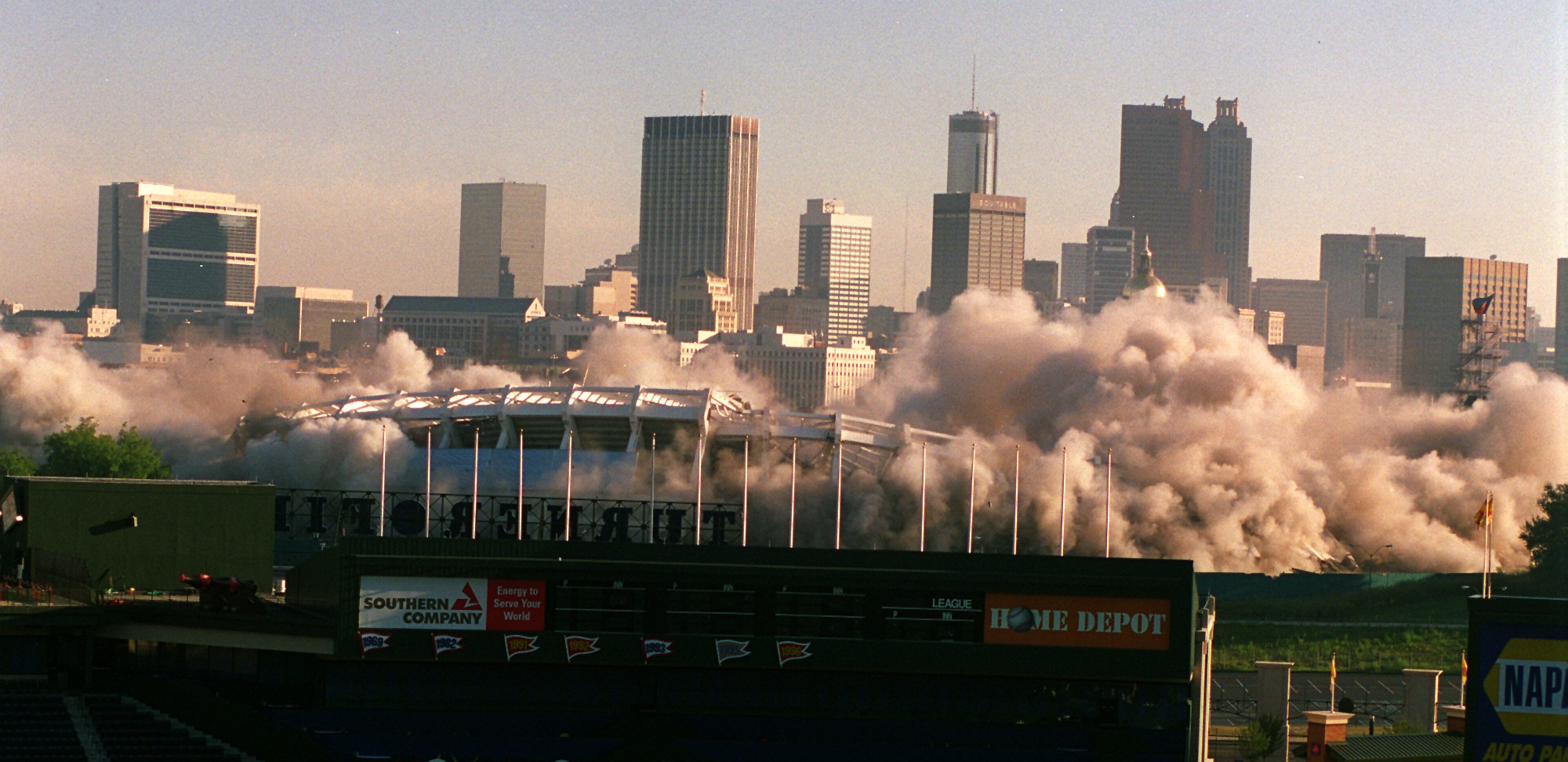 970802 - Atlanta, Georgia - The imploding Historic Atlanta Fulton County Stadium is framed by the new Turner Field as it comes down with a series of 1,200 successive detonations. The space will be turned into 4,000 parking spaces. (AJC Staff Photo/Jonathan Newton)