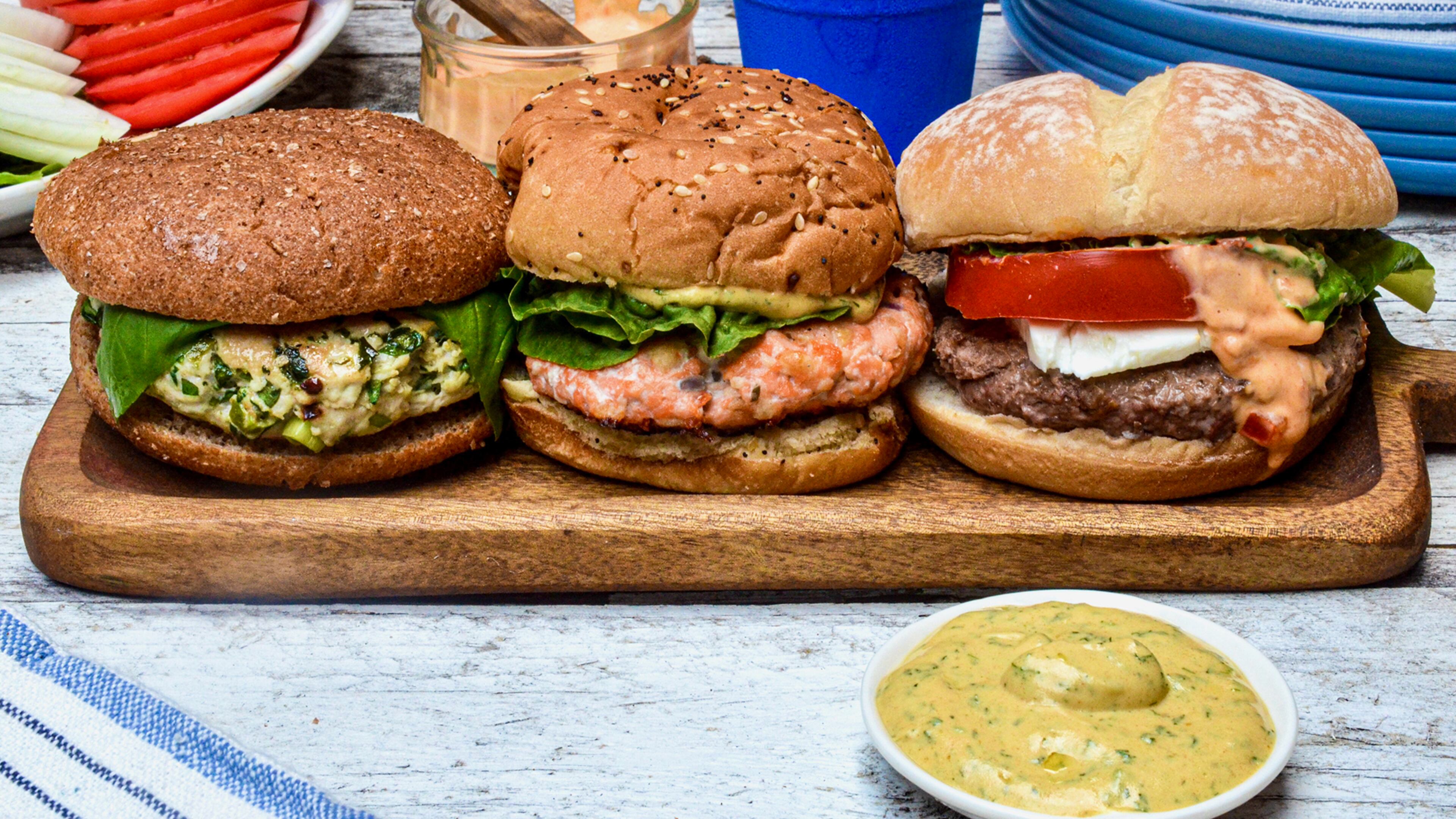Change your burger routine with a non-beef patty. Pictured, from left to right, are a Blue Cheese-Stuffed Turkey Burger, Salmon Burger with Mustard Dill Sauce, and Lamb Burger with Harissa Mayonnaise. Virginia Willis/For the AJC
(Virginia Willis for The Atlanta Journal-Constitution)