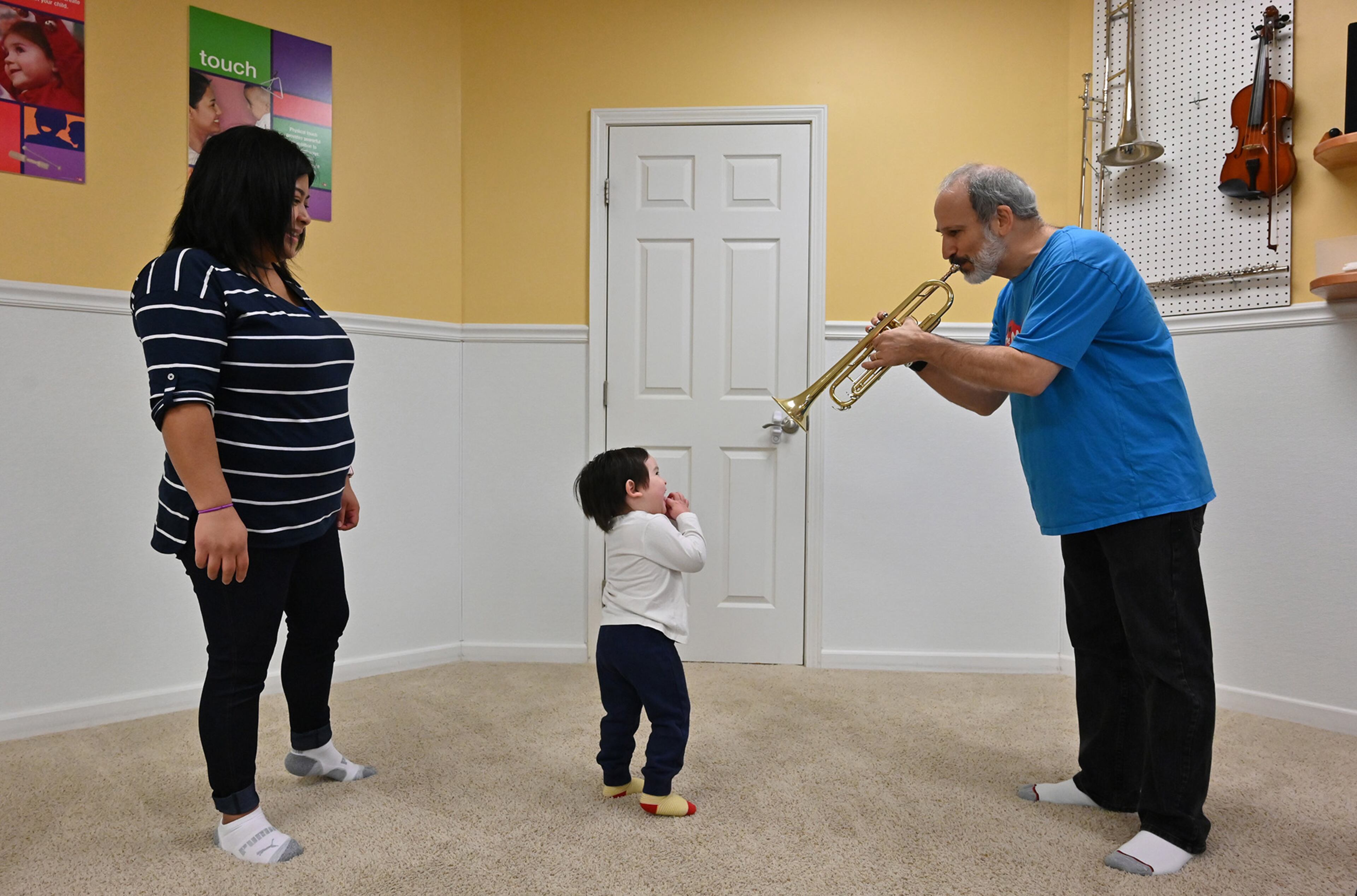 February 20, 2020 Dunwoody - Rob Sayer (right), Founder and CEO, plays the trumpet for Emmett White, 2, as his mother Lilian Hilerio (left) looks at The Music Class Inc (TMC), an international music education program, in Dunwoody on Thursday, February 20, 2020. The Music Class, provides music and movement classes for families with young children. They partnered with a large early childhood education company in China (https://www.rybbaby.com/tmc.html) where they teach the program. Over 20,000 families in China attending the classes there across the country. With classes cancelled in China during the outbreak and our families there stuck at home they are filming classes here in Atlanta and broadcasting them free on a WeChat channel in China. (Hyosub Shin / Hyosub.Shin@ajc.com)
