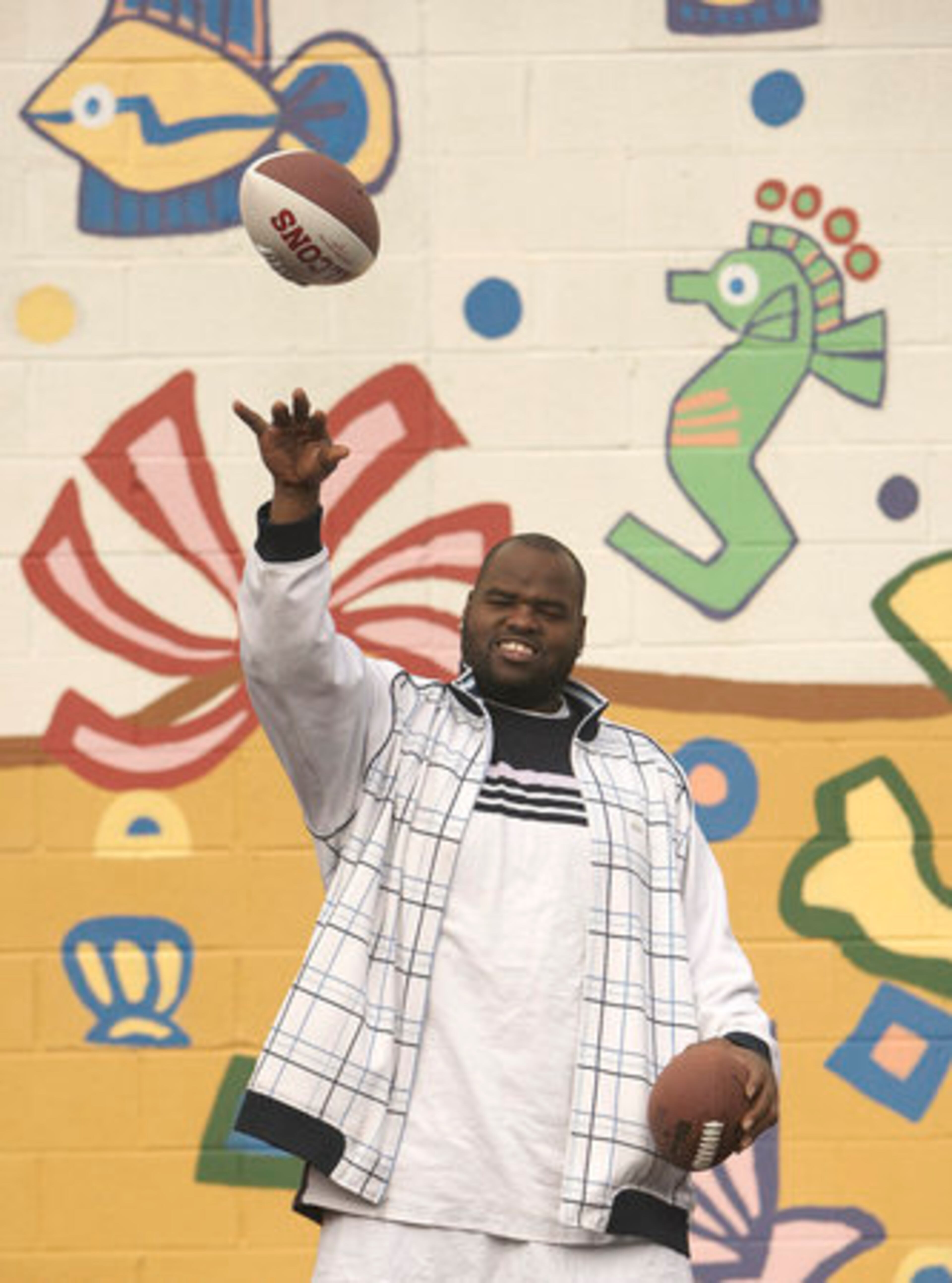 Kindal Moorehead tosses around some footballs with some boys staying at the shelter, which on average serves between 150 and 250 women and children daily.