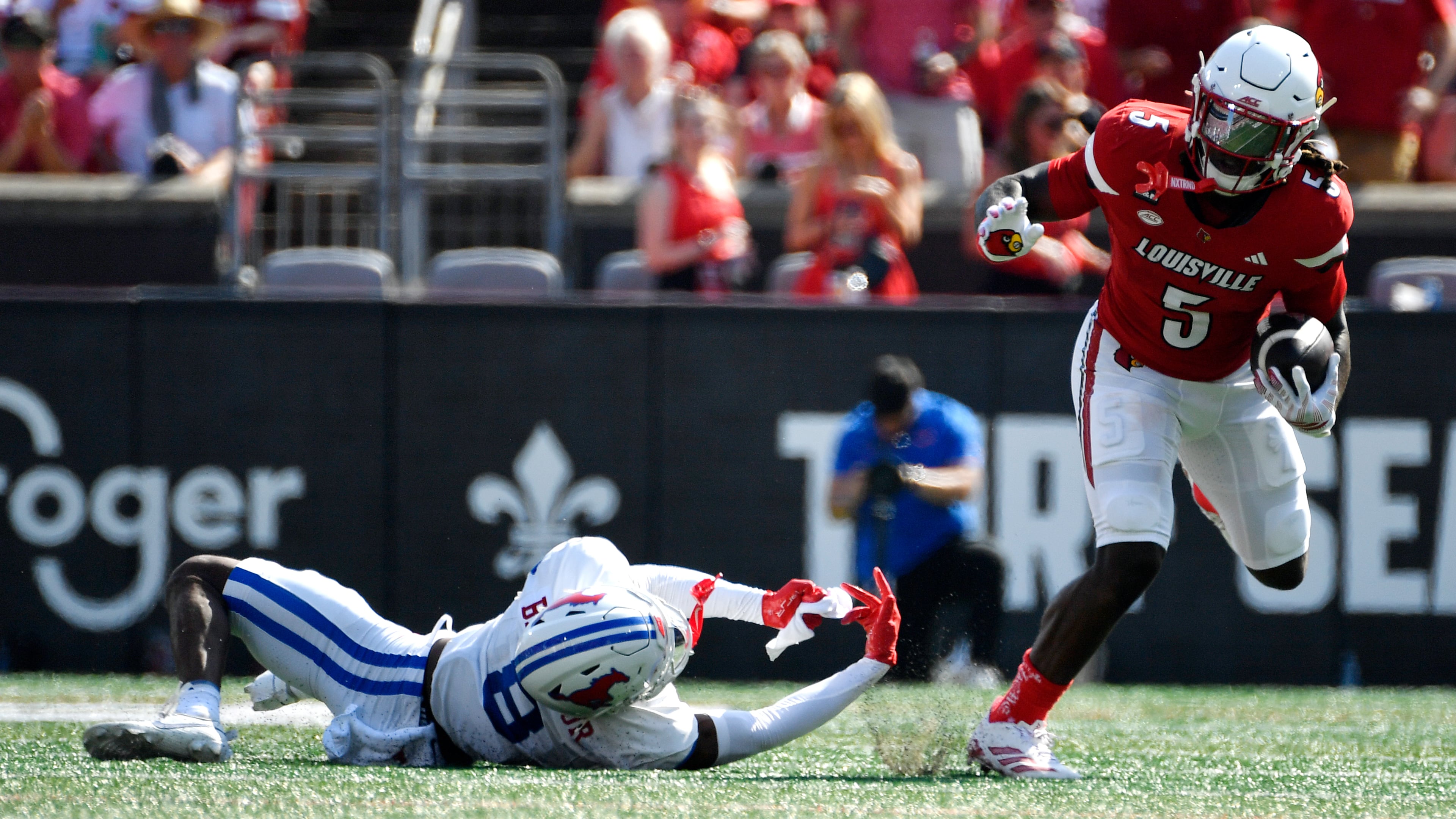 Louisville running back Keyjuan Brown (5) runs from a tackle-attempt by SMU cornerback Marcellus Barnes Jr. (8) during the first half of an NCAA college football game in Louisville, Ky., Saturday, Sept. 19, 2026. (AP Photo/Timothy D. Easley)