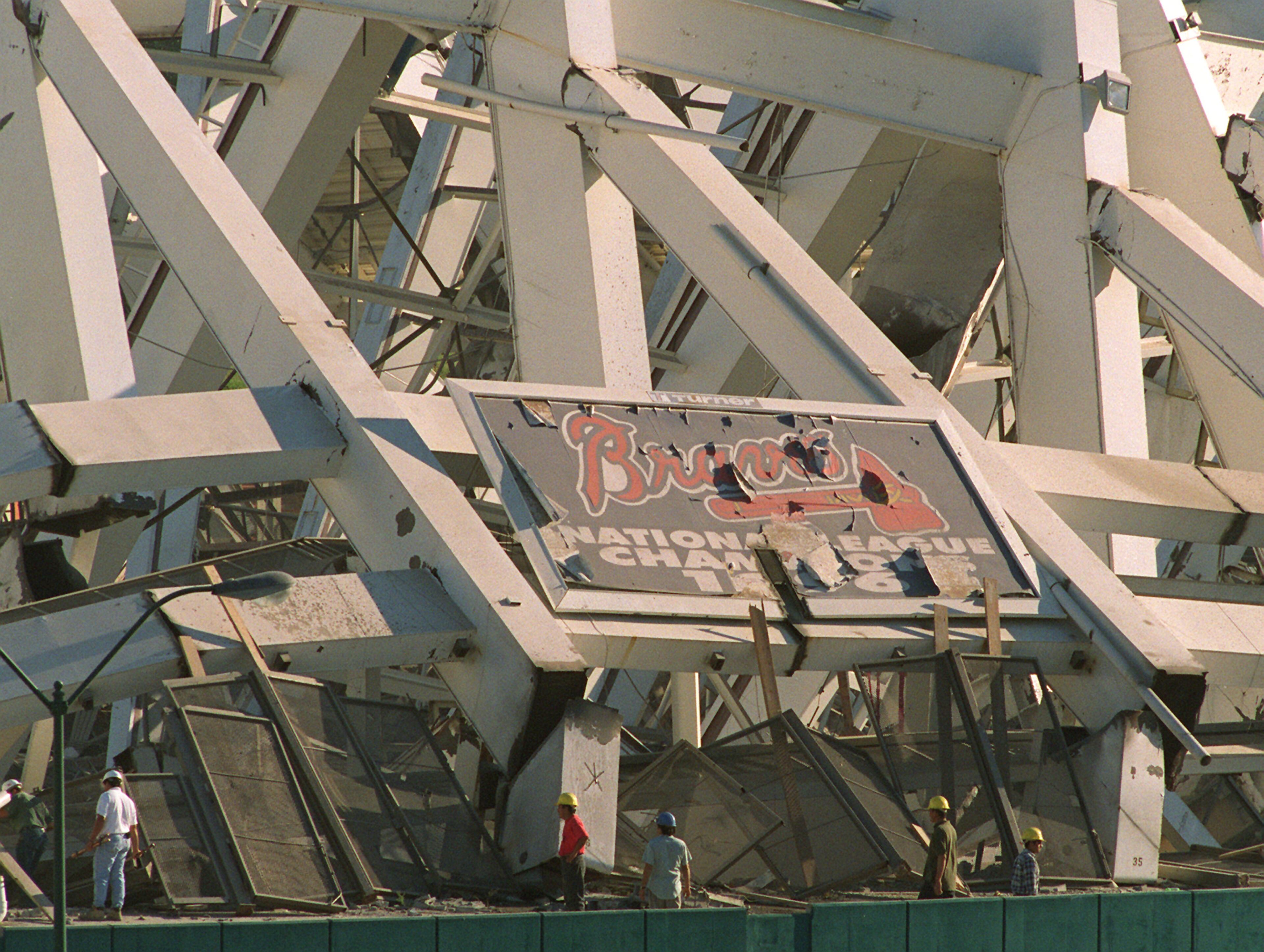 970802 ATLANTA: With the Atlanta Braves 1996 National League Championship billboard still attatched to the twisted frame of Atlanta Fulton County Stadium Demolition crew members inspect their handy work after imploding it down with a series of 1,200 successive detonations. The space will be turned into 4,000 parking spaces. (AJC Staff Photo/Jonathan Newton) 8/97