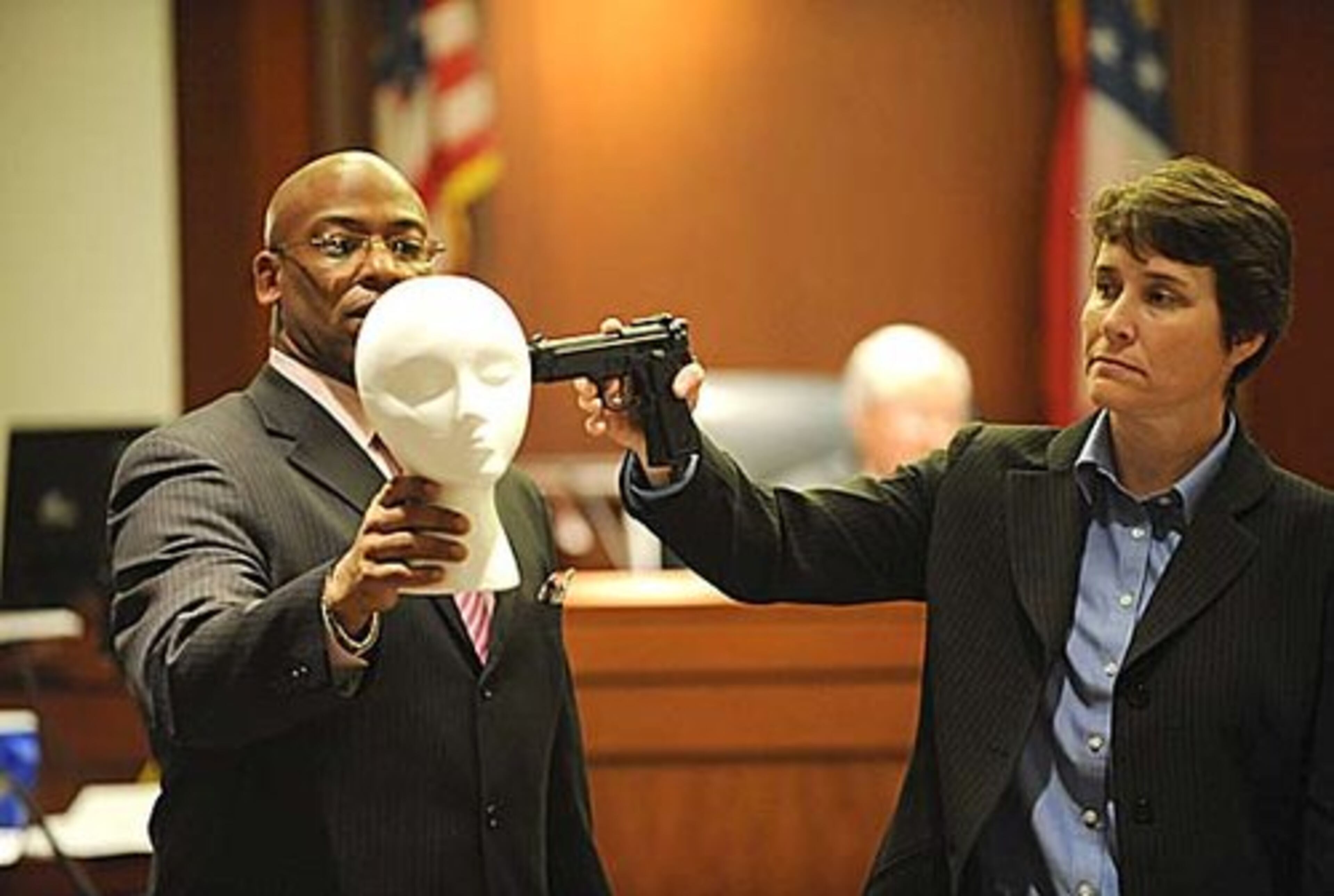Bernadette Davy, firearms examiner at Georgia State Crime Lab, demonstrates a contact gun shot during testimony Friday.