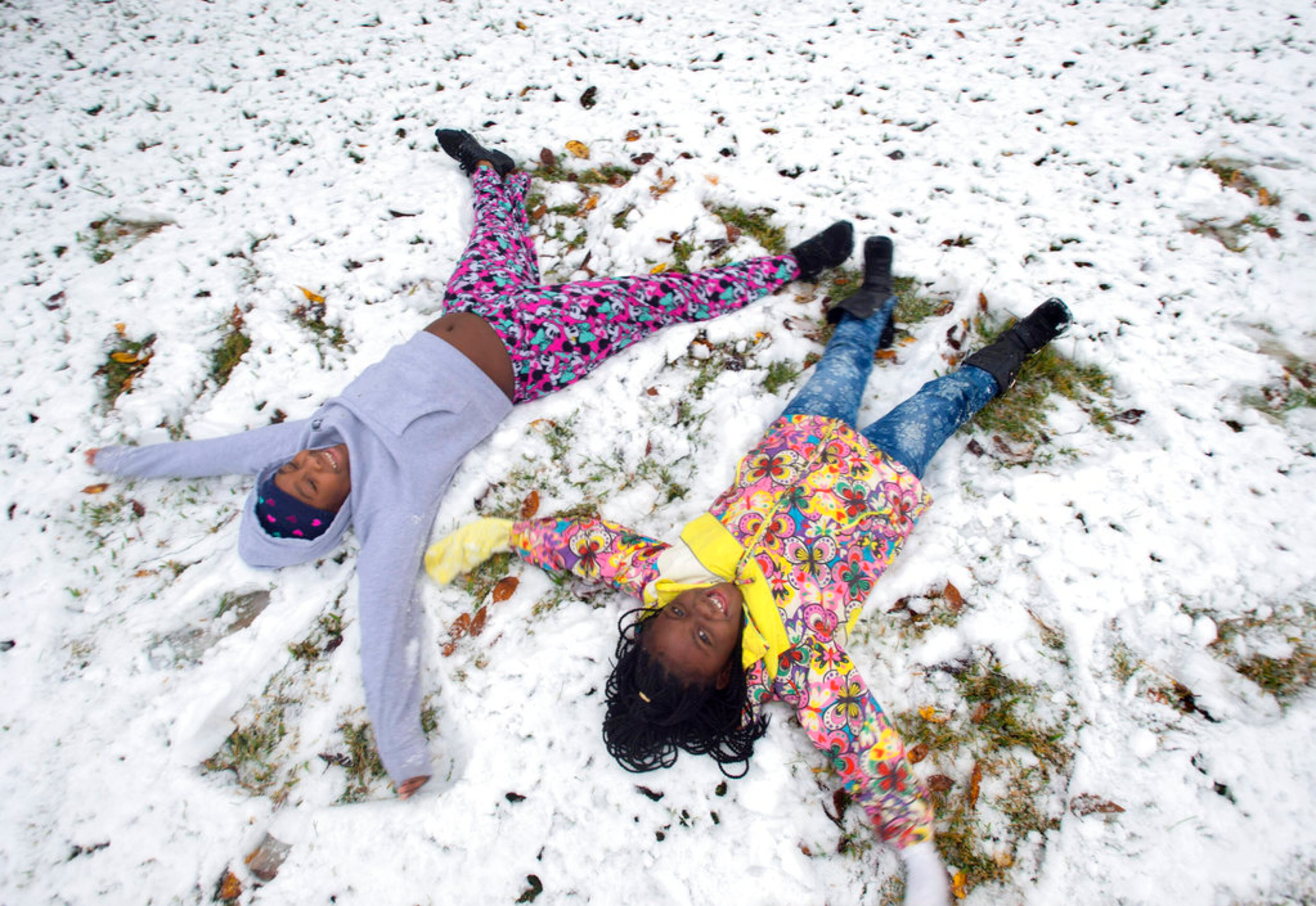 Kasey Brown, 11, left, and her friend Destiny Minor, 7, make snow angels on a lawn on their street, West Grant, Friday, Dec. 8, 2017, after an unusual snowfall in Baton Rouge, La. Kasey's father Dlaniger Brown said the girls were enjoying the snow, and had been outside several times already, but were especially happy just to be home from school for the day. (Travis Spradling/The Advocate via AP)