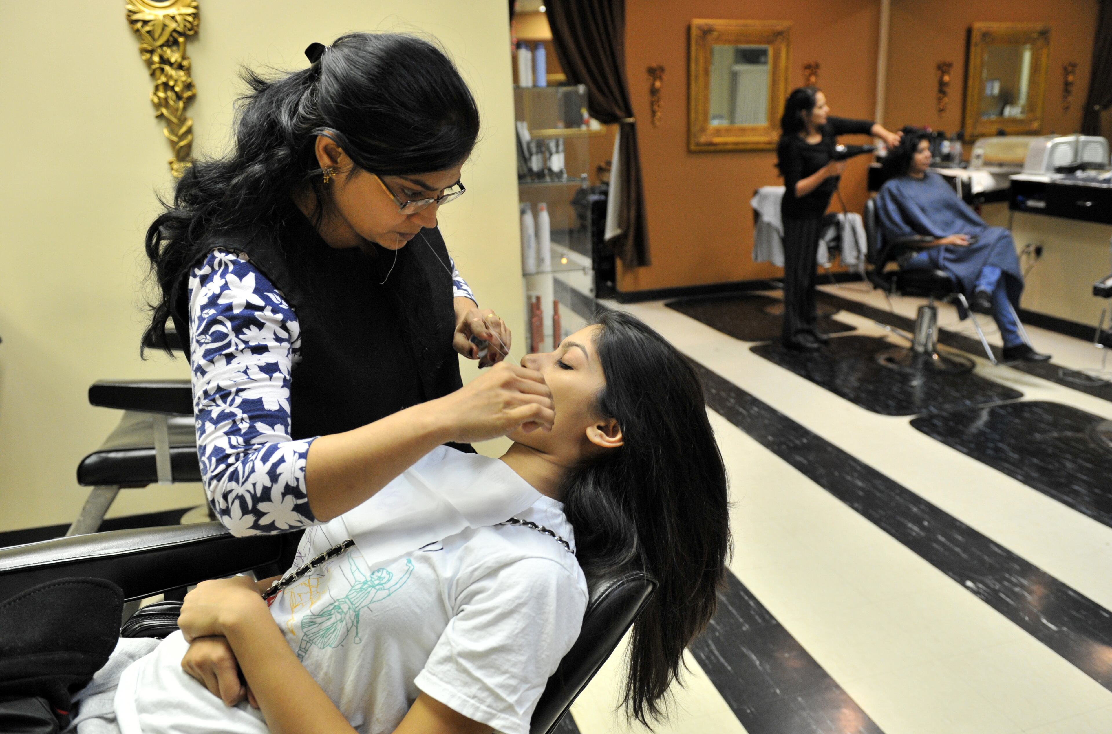 Alicia Gopichund of Johns Creek has her eyebrows threaded by Indian threader Meghane Saxena at Stylz Beauty & Hair in Duluth on Nov. 24. Alicia Gopichund comes to this popular Indian salon every month to get her her eyebrows threaded.
