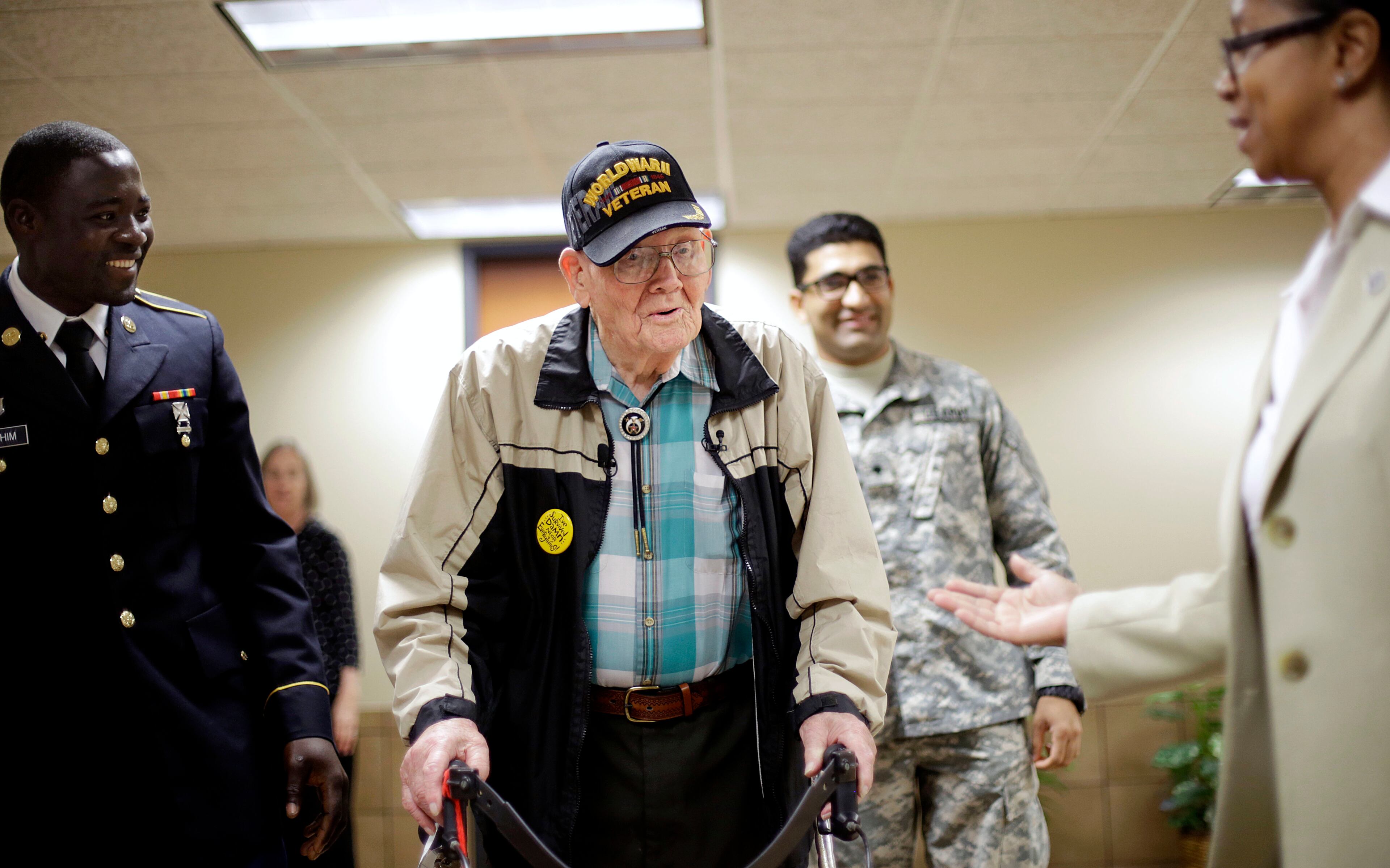 Ninety-four-year-old World War II veteran Sherwin Callander, center, arrives for a naturalization ceremony with U.S. Army Spc. Gulam Ali, background right, originally from India, and U.S. Army Spc. Iddrisu Ibrahim, left, originally of Ghana, Monday, June 2, 2014, in Atlanta.