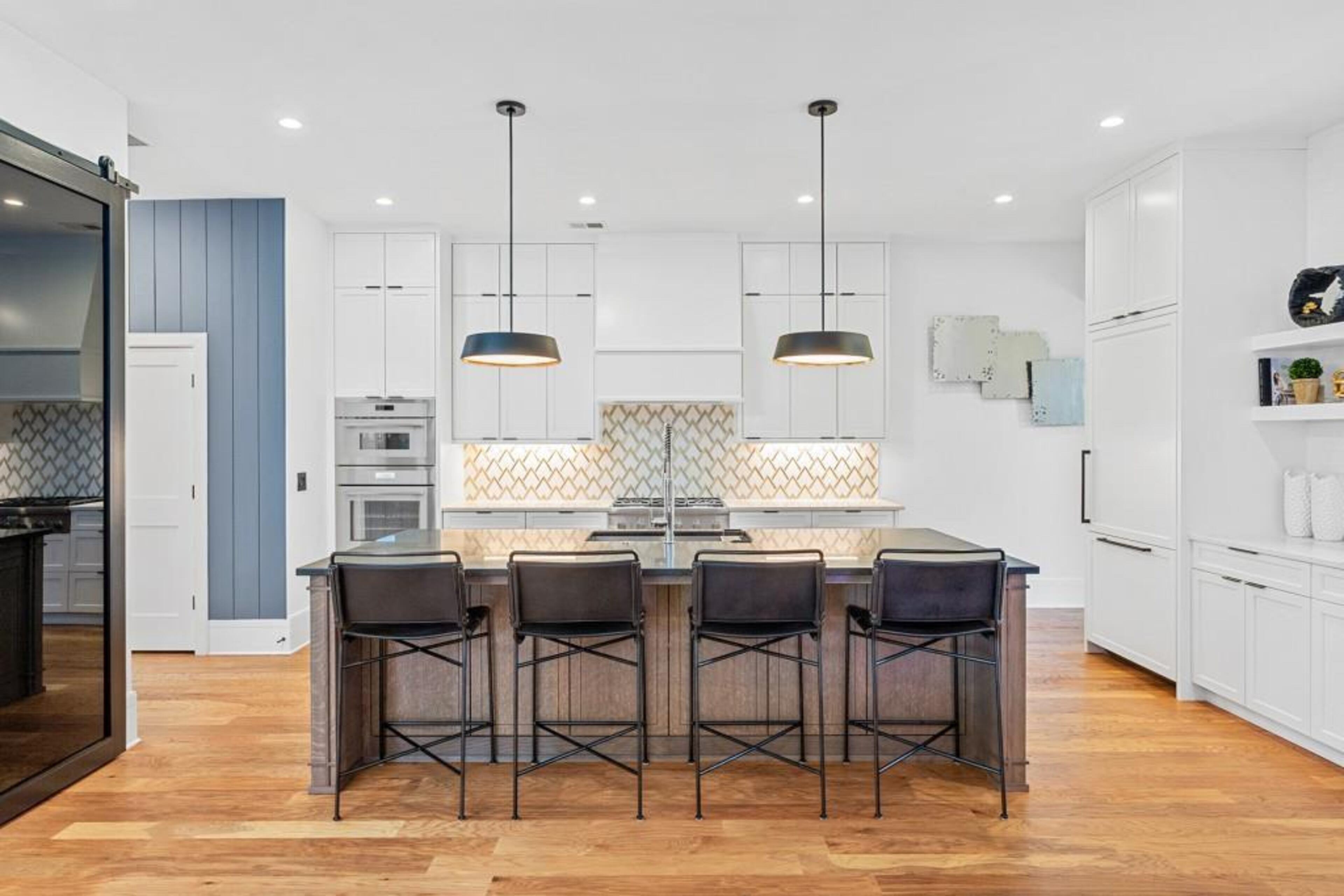 Chef's kitchen featuring oversized island with honed quartzite countertops, commercial grade stainless steel appliance package, custom backsplash, walk-in pantry and an abundance of storage space.