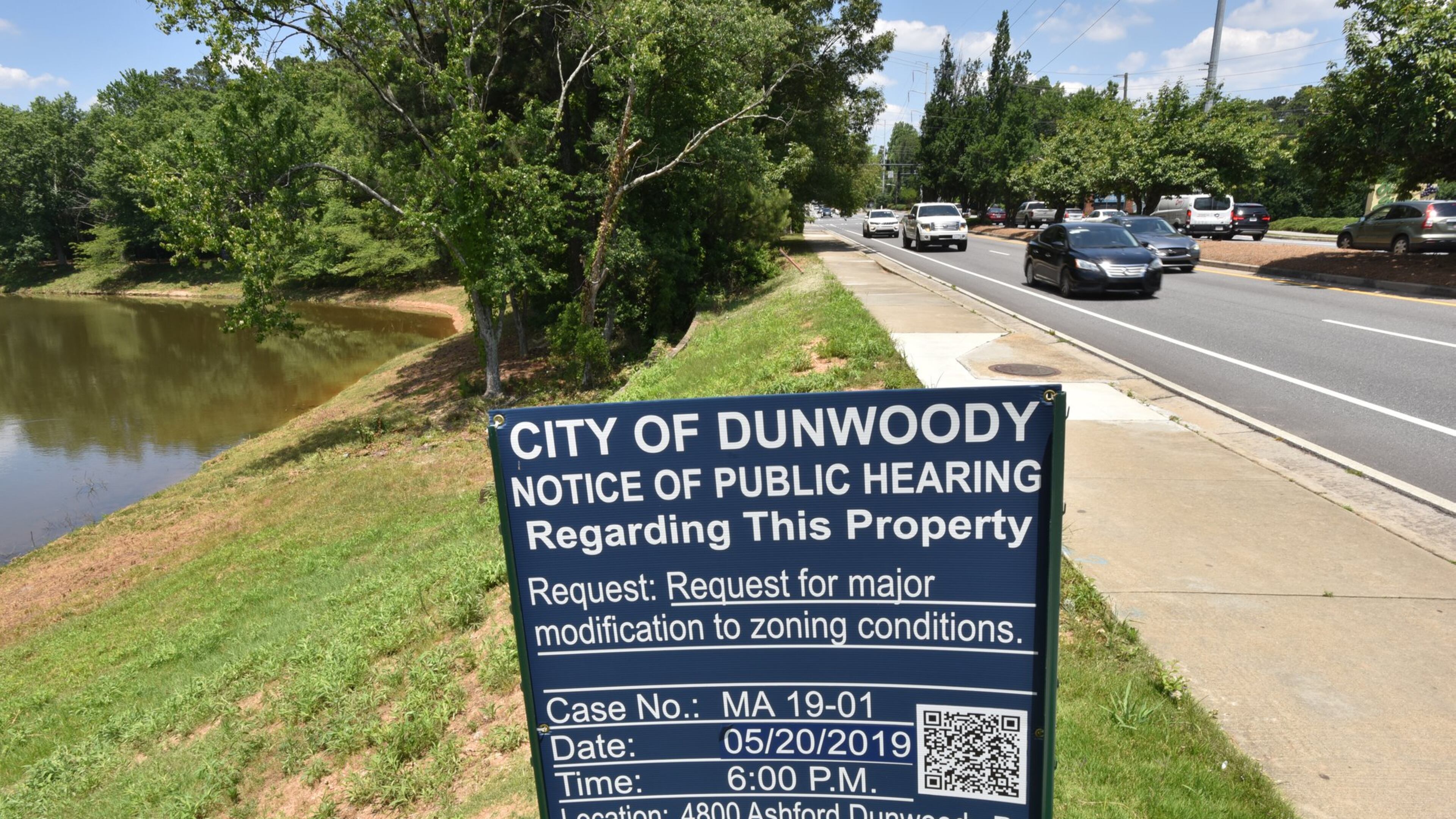 A “Notice of Public Hearing” sign is posted near Ashford Dunwoody Road in Dunwoody where developers hope to redevelop an old restaurant hub in the Perimeter Center area, adding a gas station, grocery store, a bank and a new road. HYOSUB SHIN / HSHIN@AJC.COM