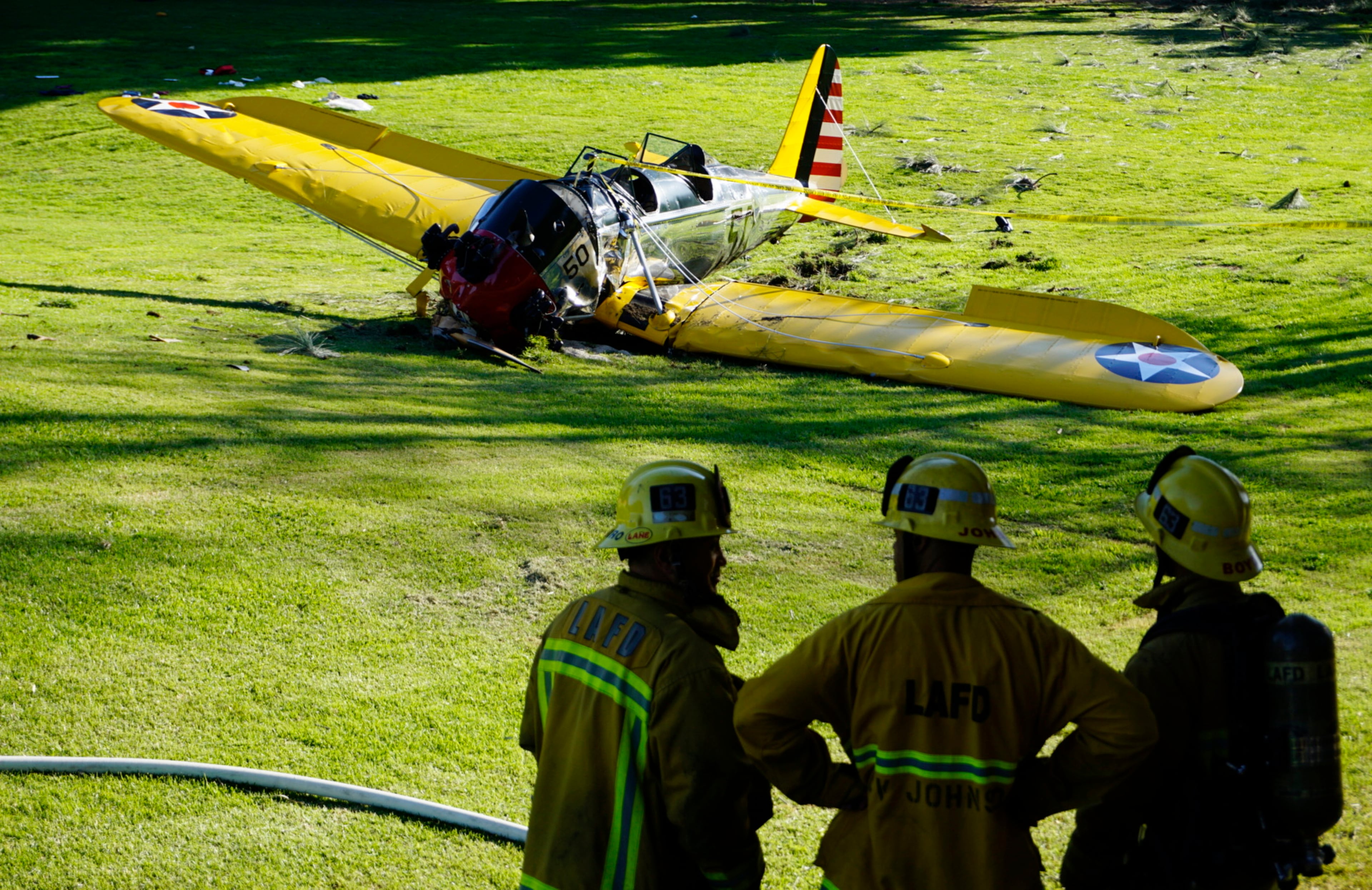 Officials stand near the scene of a small vintage airplane that crash-landed on the Penmar Golf Course in the Venice area of Los Angeles, Thursday, March 5, 2015. Harrison Ford crash-landed the airplane shortly after taking off from a nearby airport and reporting engine problems. (AP Photo/Damian Dovarganes)