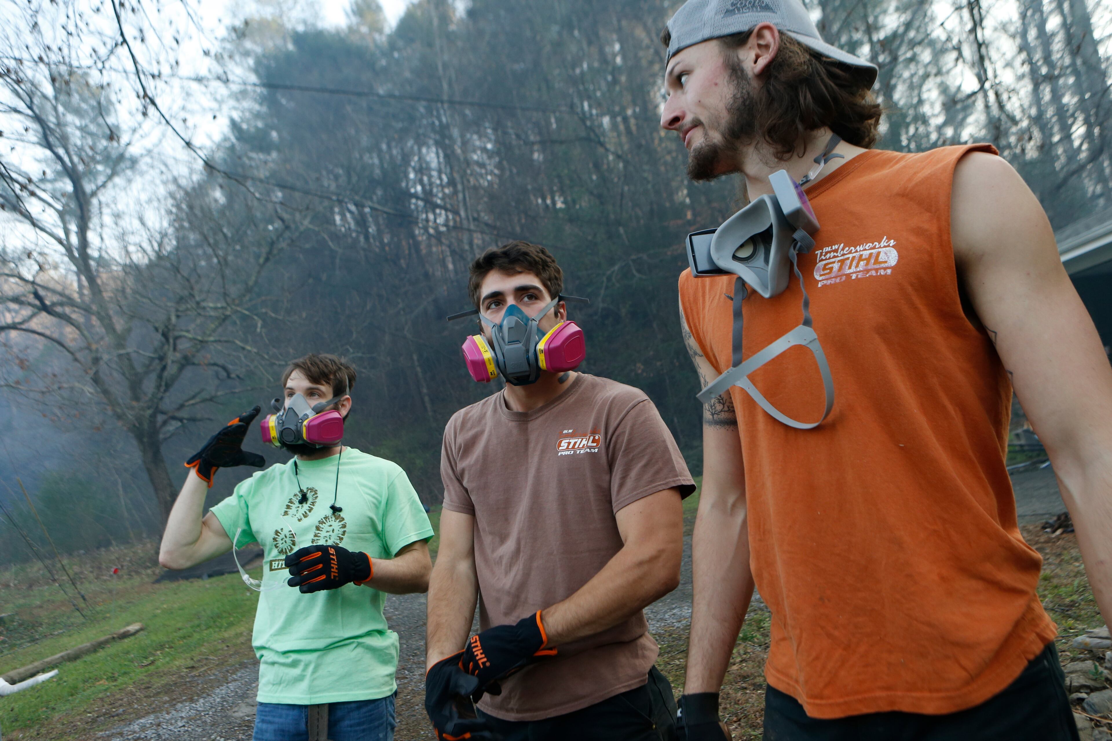 GATLINBURG, TN - NOVEMBER 29: (L-R) Residents Kirk Wallace, Caleb Graves and Tyler Alden gather to clear debris and put out small fires near surrounding homes as the remains of their neighbors' homes smolder after a wildfire November 29, 2016 in Gatlinburg, Tennessee. Thousands of people have been evacuated from the area and over 100 houses and businesses were damaged or destroyed after drought conditions helped the fire spread through the foothills of the Great Smoky Mountains. (Photo by Brian Blanco/Getty Images)