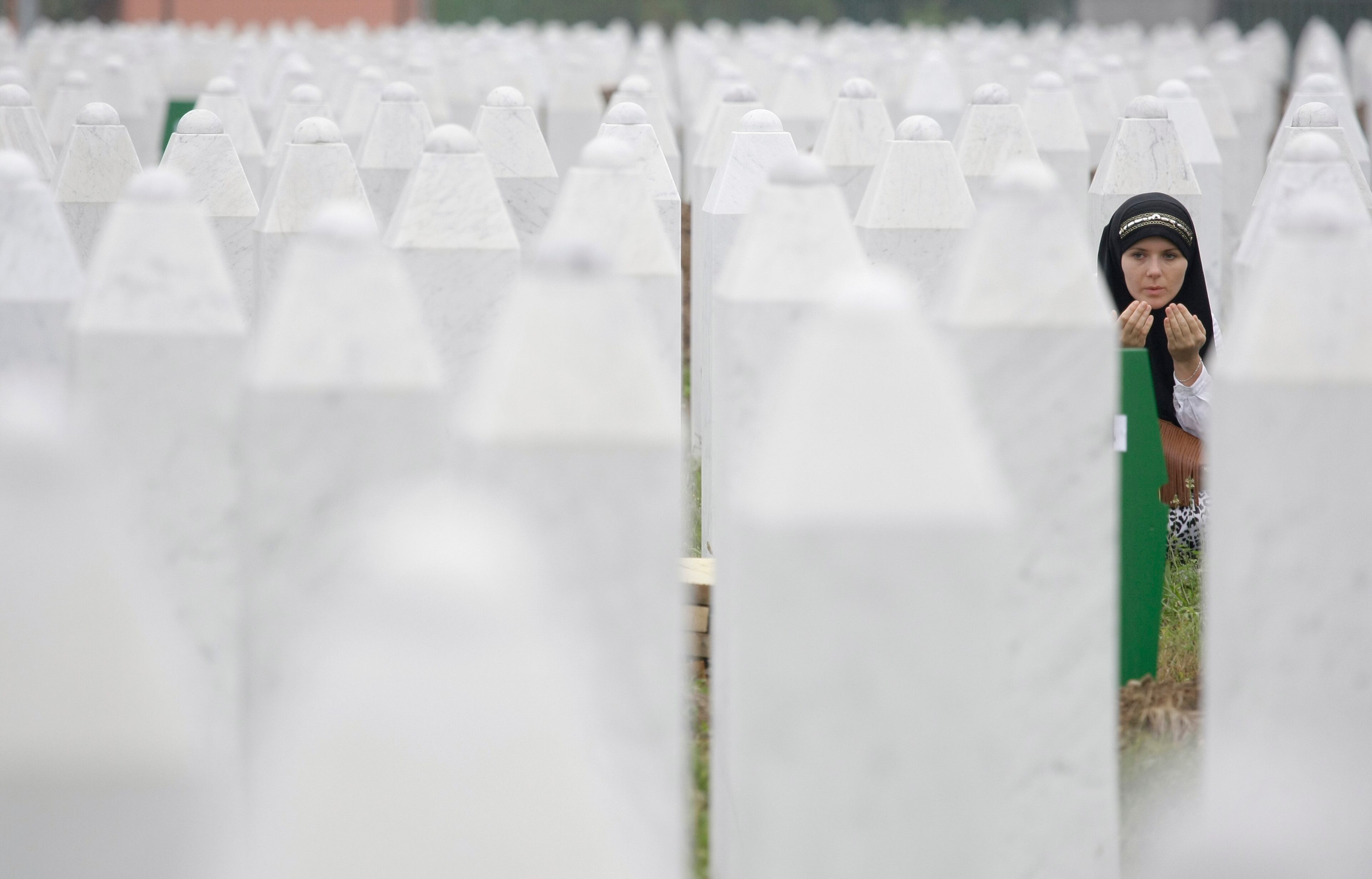 Bosnian woman Merima Nukic prays at the grave of her father during a funeral ceremony at the memorial center in Potocari, near Srebrenica, 160 kms east of Sarajevo, Bosnia, Thursday, July 11, 2013. People from around Bosnia and abroad have begun arriving in Srebrenica Thursday to commemorate 18th anniversary of the 1995 massacre and rebury recently identified victims exhumed from mass graves. The victims' bodies are still being exhumed from mass graves in the area, where Serbs had dumped them in an attempt to cover up the crime. Identified victims are buried each year on the massacre's anniversary at a memorial cemetery near Srebrenica. (AP Photo/Amel Emric)