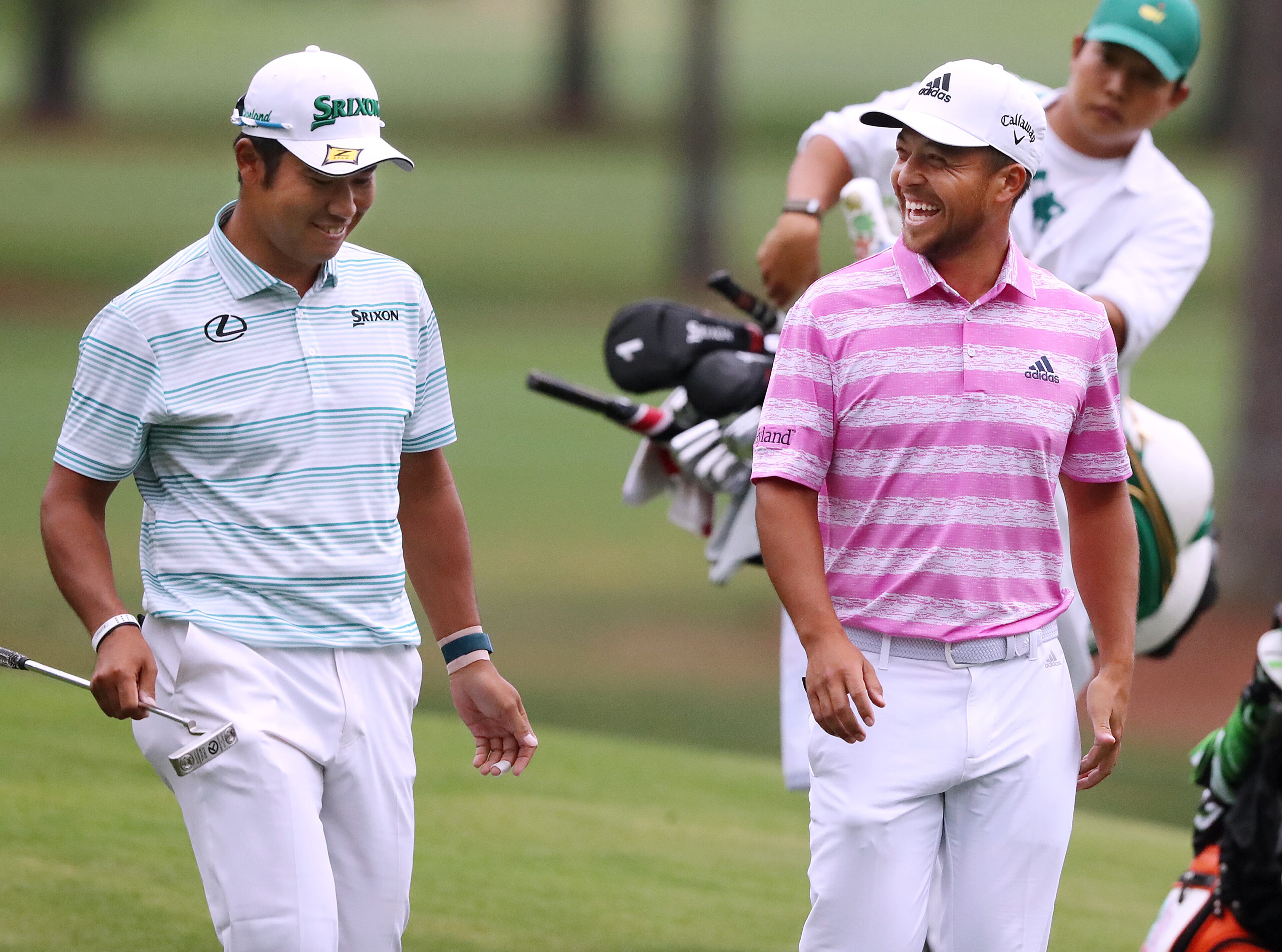 041021 Augusta: — A PAIR OF EAGLES — Hideki Matsuyama and Xander Schauffele share a laugh after they both made eagle putts on the 15th green during the third round of the Masters on Saturday, April 10, 2021, in Augusta. “Curtis Compton / Curtis.Compton@ajc.com”